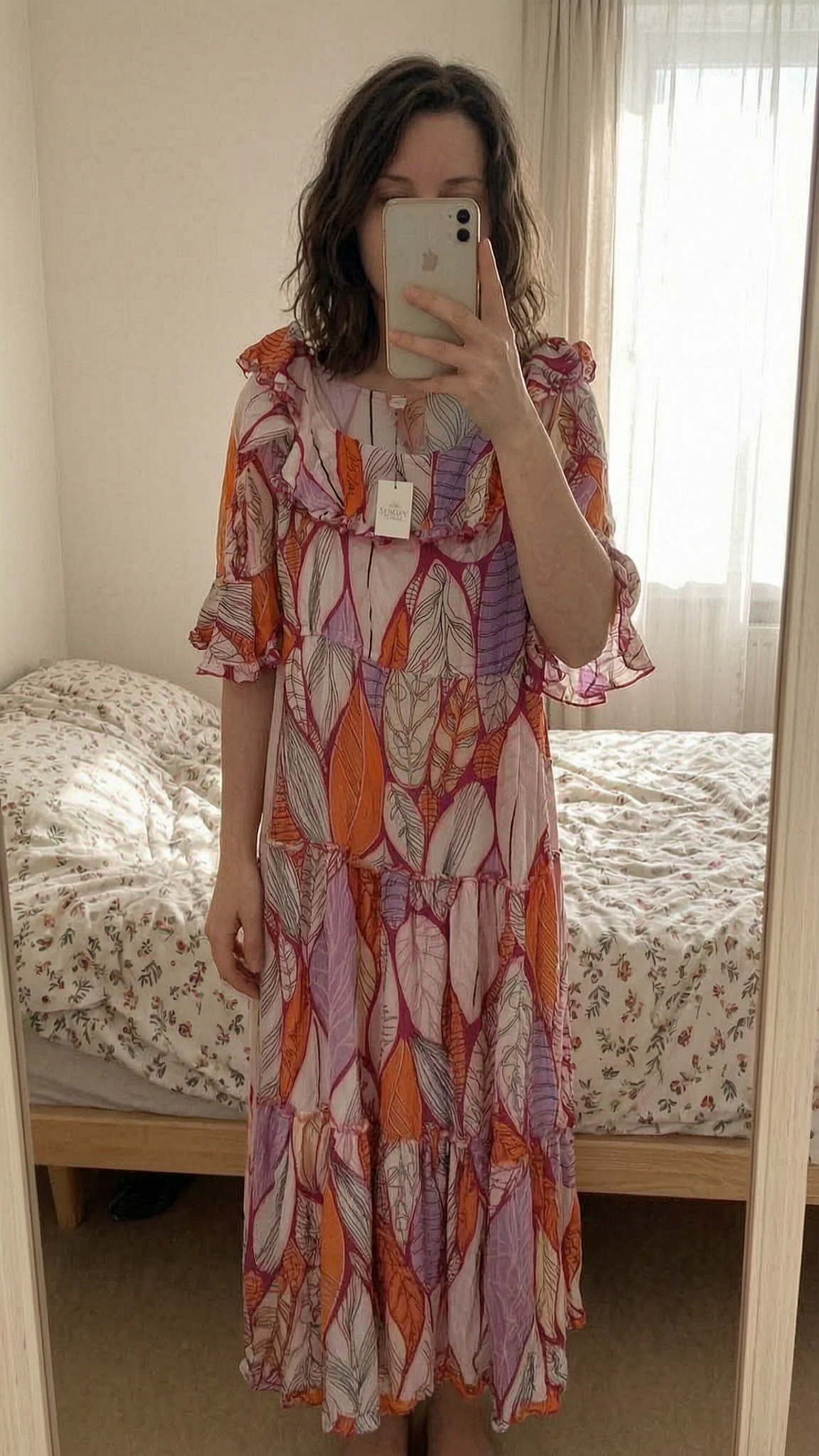 Magnifique robe d'été debout, face à la caméra, dans une chambre à la lumière douce, avec une lumière naturelle filtrant par la fenêtre.