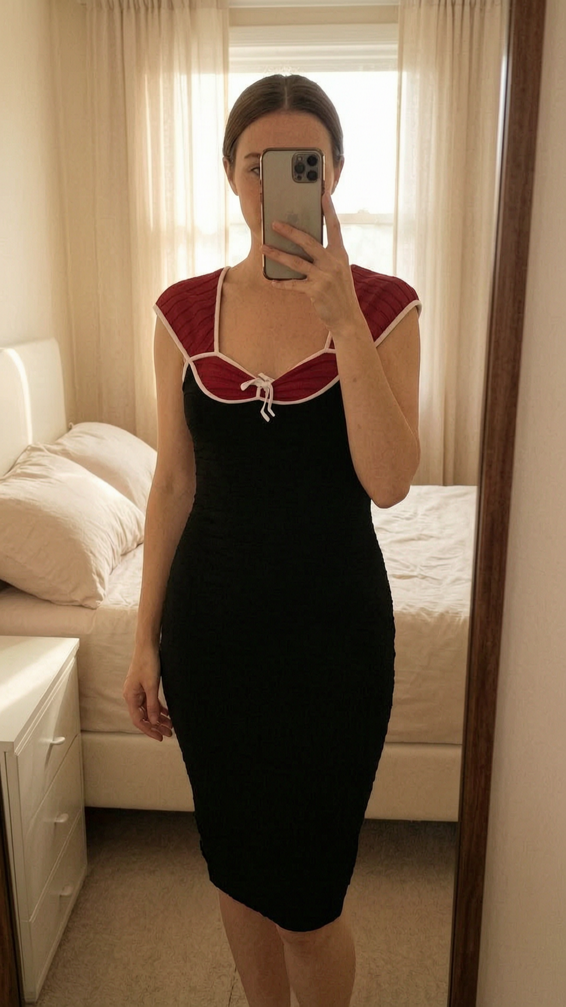 Robe Morgan debout, face à la caméra, dans une chambre à la lumière douce, avec une lumière naturelle filtrant par la fenêtre.