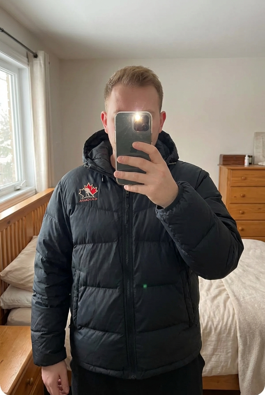 Une personne en Doudoune Puffer Jacket Vintage Année 90 Nike Canada Hockey Noir L debout, face à la caméra, avec une silhouette légèrement plus ronde, dans une chambre à la lumière douce, avec une lumière naturelle filtrant par la fenêtre.