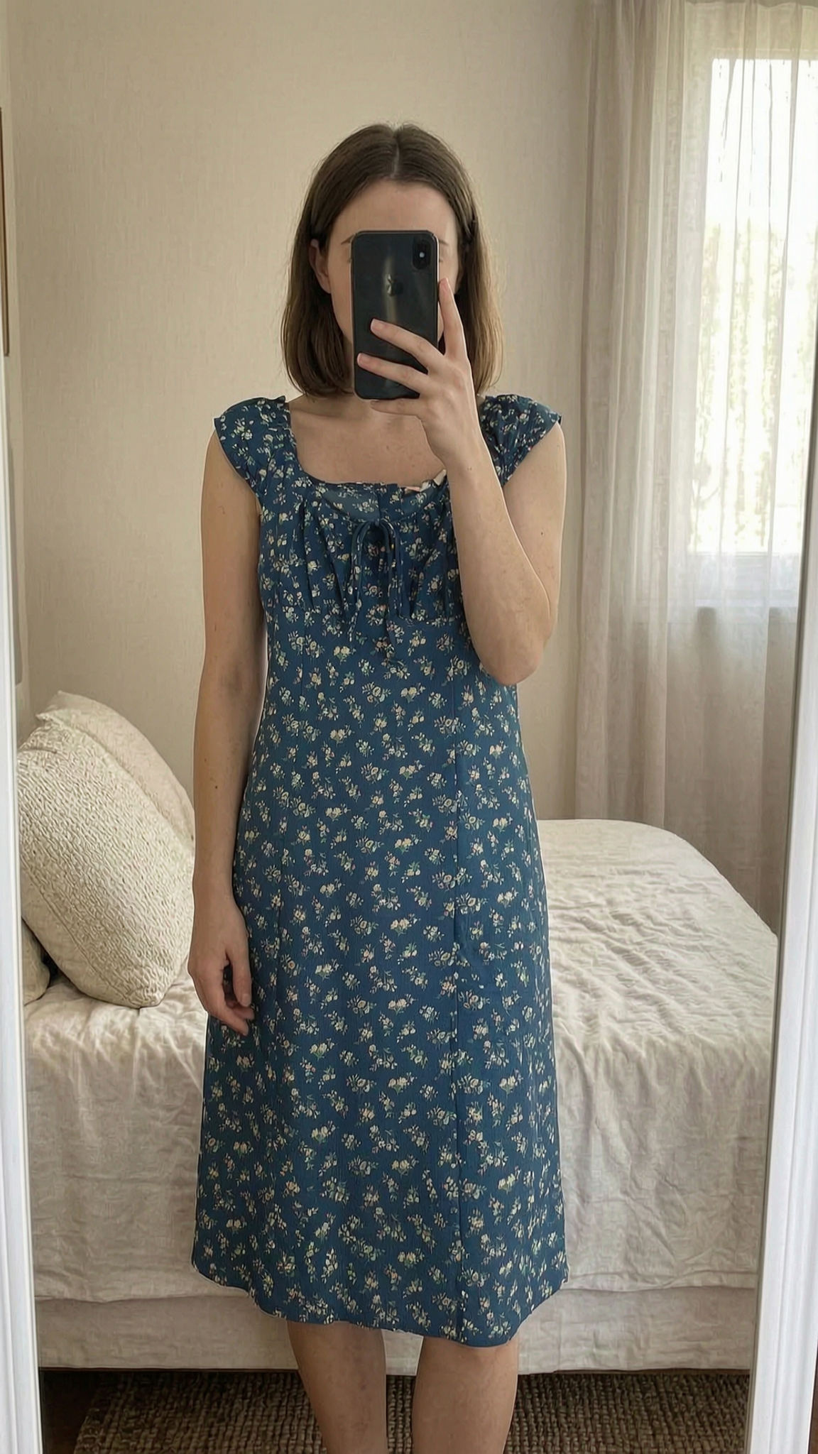 Robe été femme L fleurie debout, face à la caméra, dans une chambre à la lumière douce, avec une lumière naturelle filtrant par la fenêtre.