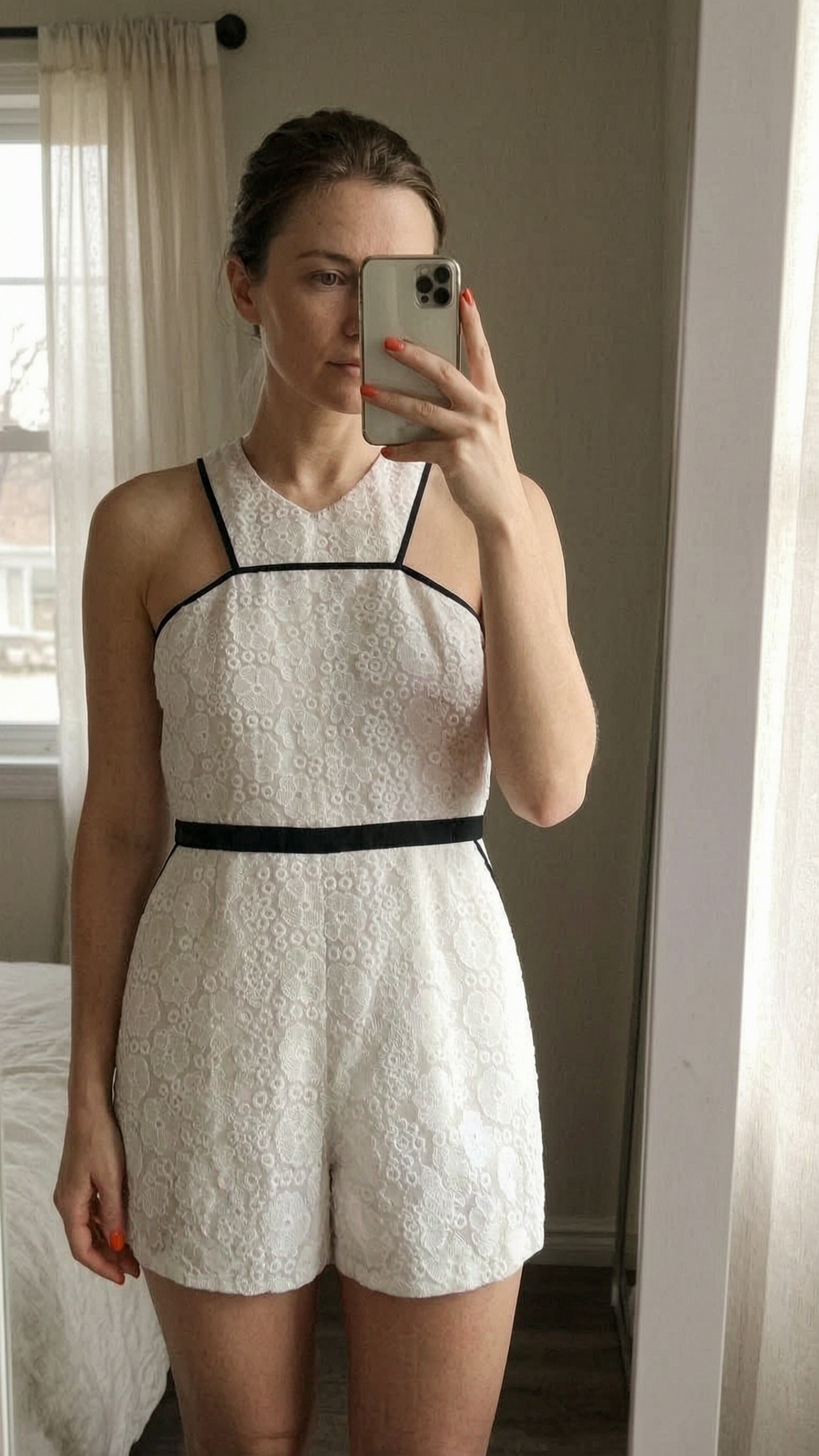 River Island cream cotton broderie anglaise halterneck playsuit - size 16 standing straight facing the camera, in a softly lit bedroom setting, with gentle natural light filtering through a window.