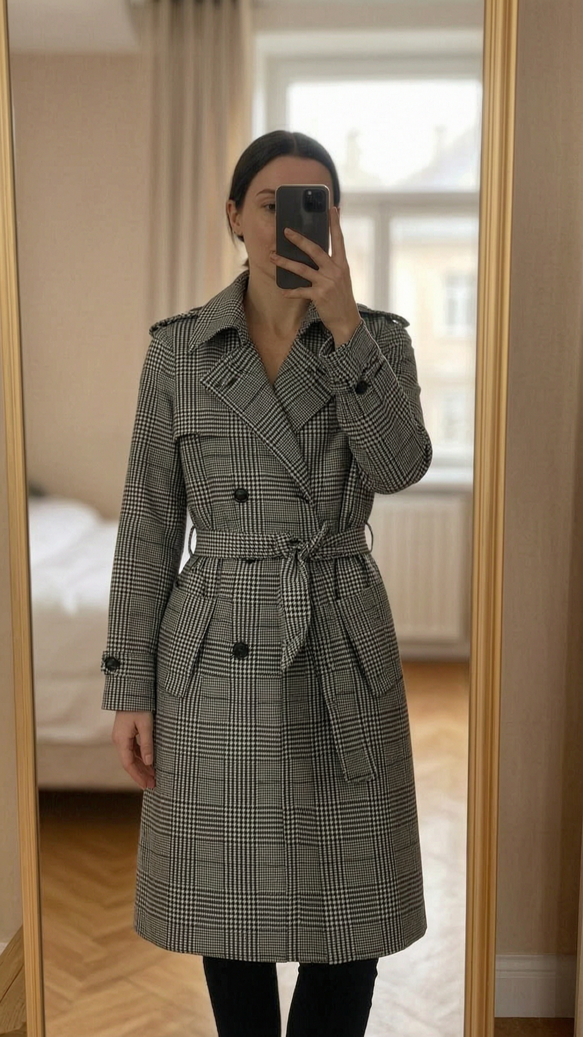 Trench Ralph Lauren, taille 0, comme neuf, noir et blanc debout, face à la caméra, dans une chambre à la lumière douce, avec une lumière naturelle filtrant par la fenêtre.