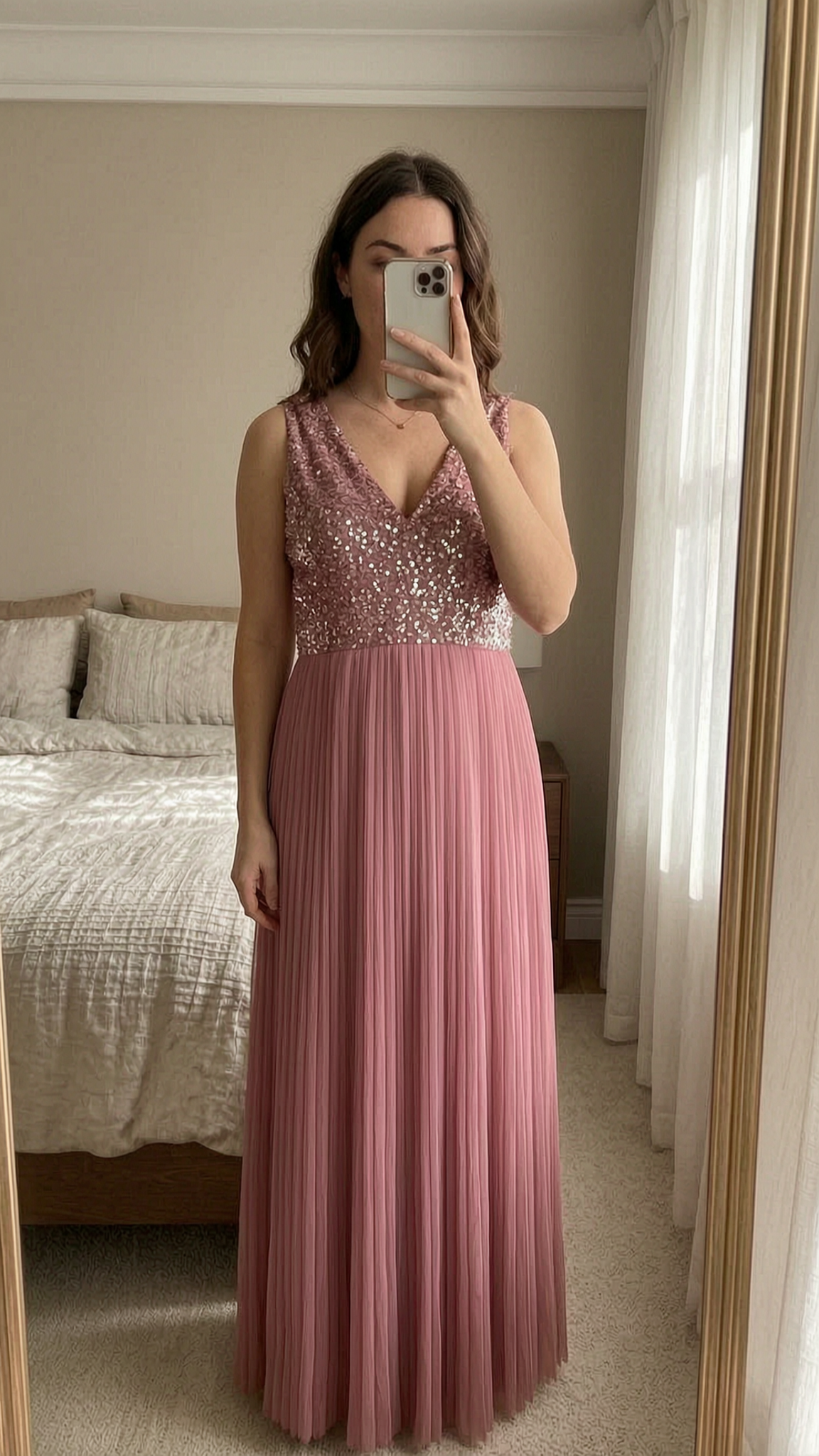 Maya Deluxe V-Neckline Pinkes Kleid aufrecht stehend, der Kamera zugewandt, in einem sanft beleuchteten Schlafzimmer, mit natürlichem Licht, das durch ein Fenster fällt.