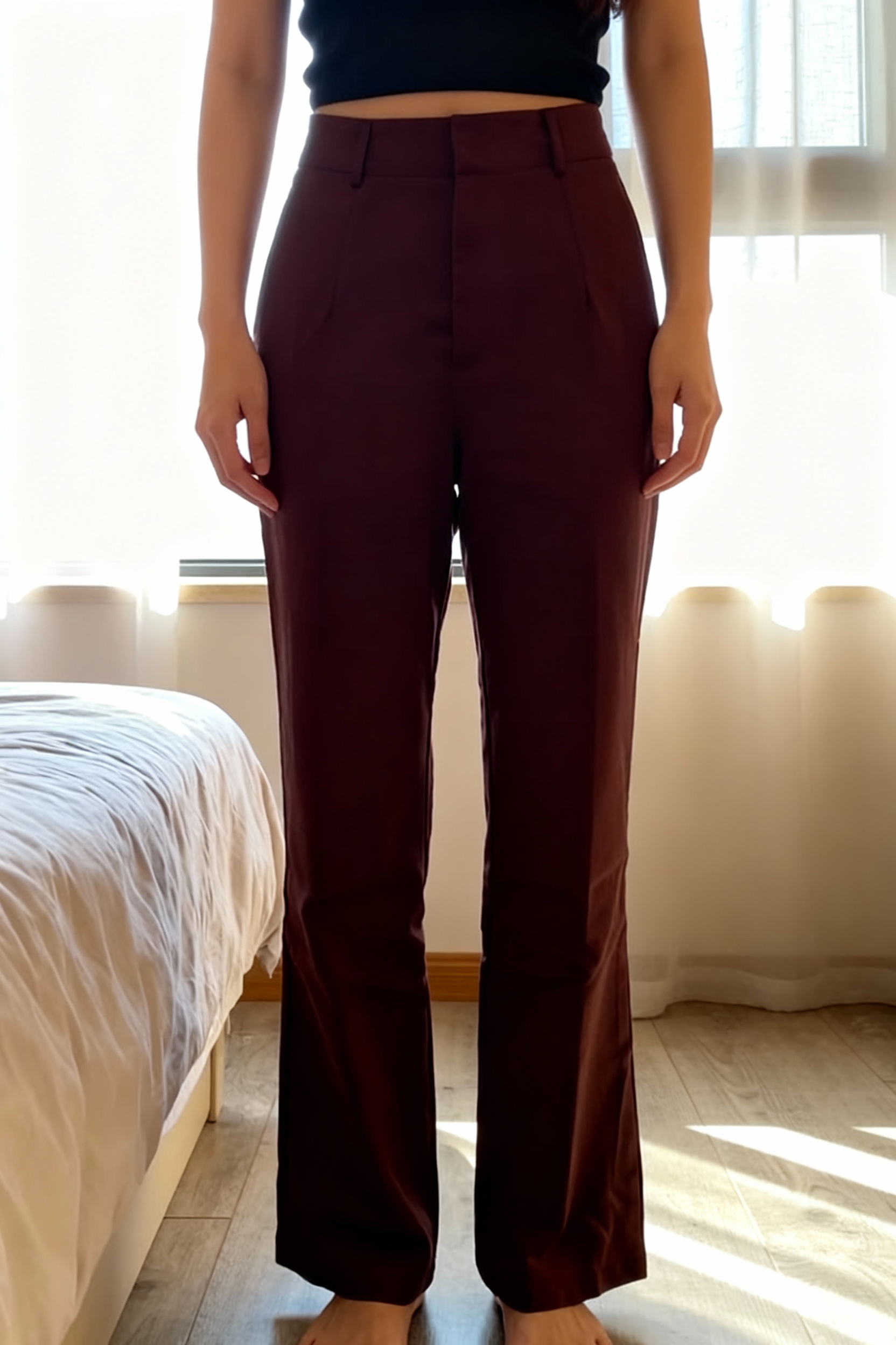 Pantalon droit debout, face à la caméra, dans une chambre à la lumière douce, avec une lumière naturelle filtrant par la fenêtre.