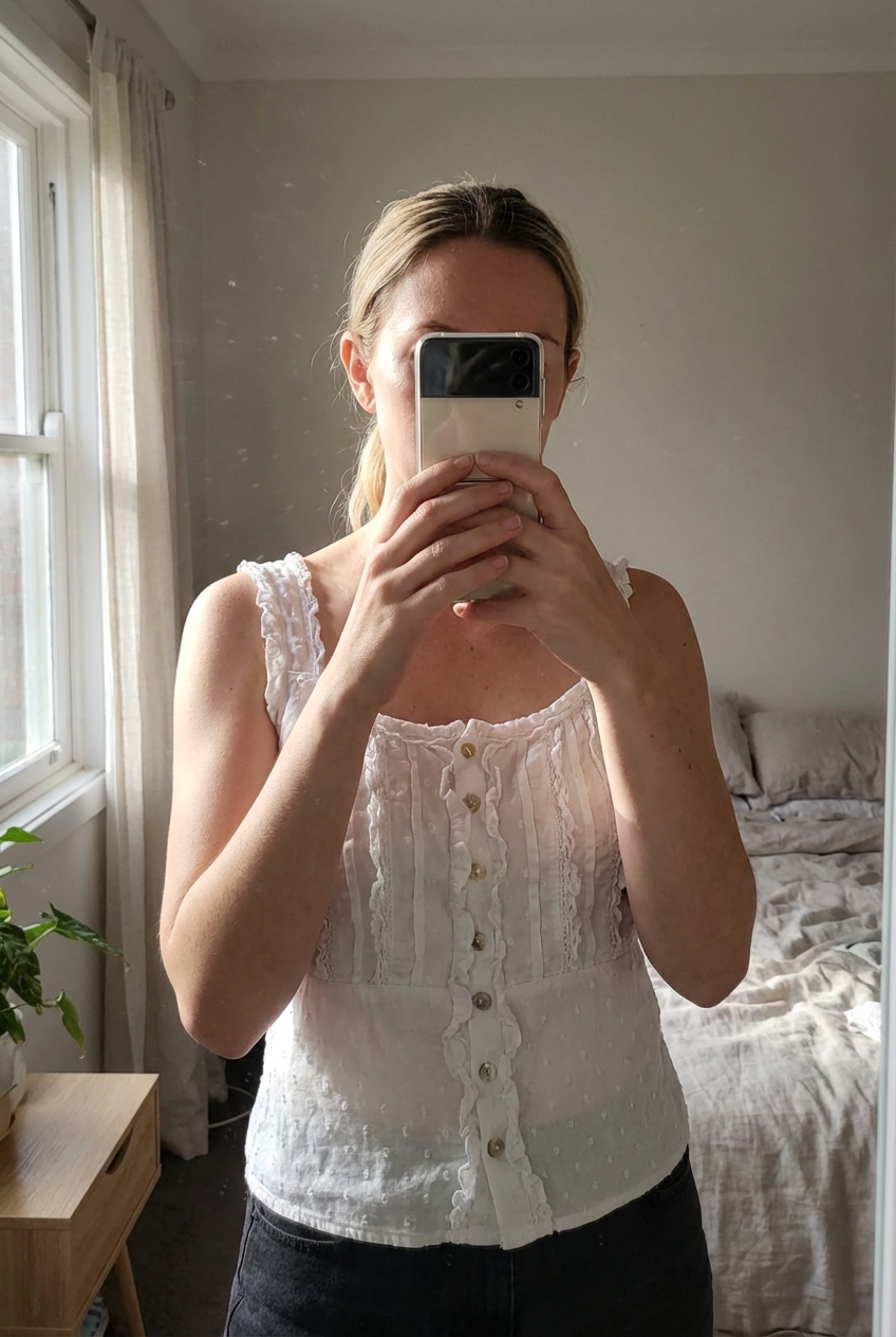 Débardeurs bohème debout, face à la caméra, dans une chambre à la lumière douce, avec une lumière naturelle filtrant par la fenêtre.