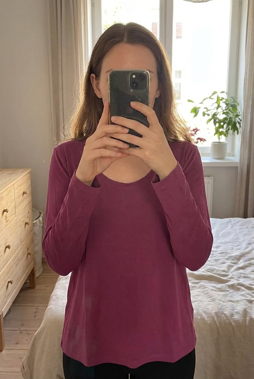 Pull femme taille xxxl debout, face à la caméra, dans une chambre à la lumière douce, avec une lumière naturelle filtrant par la fenêtre.