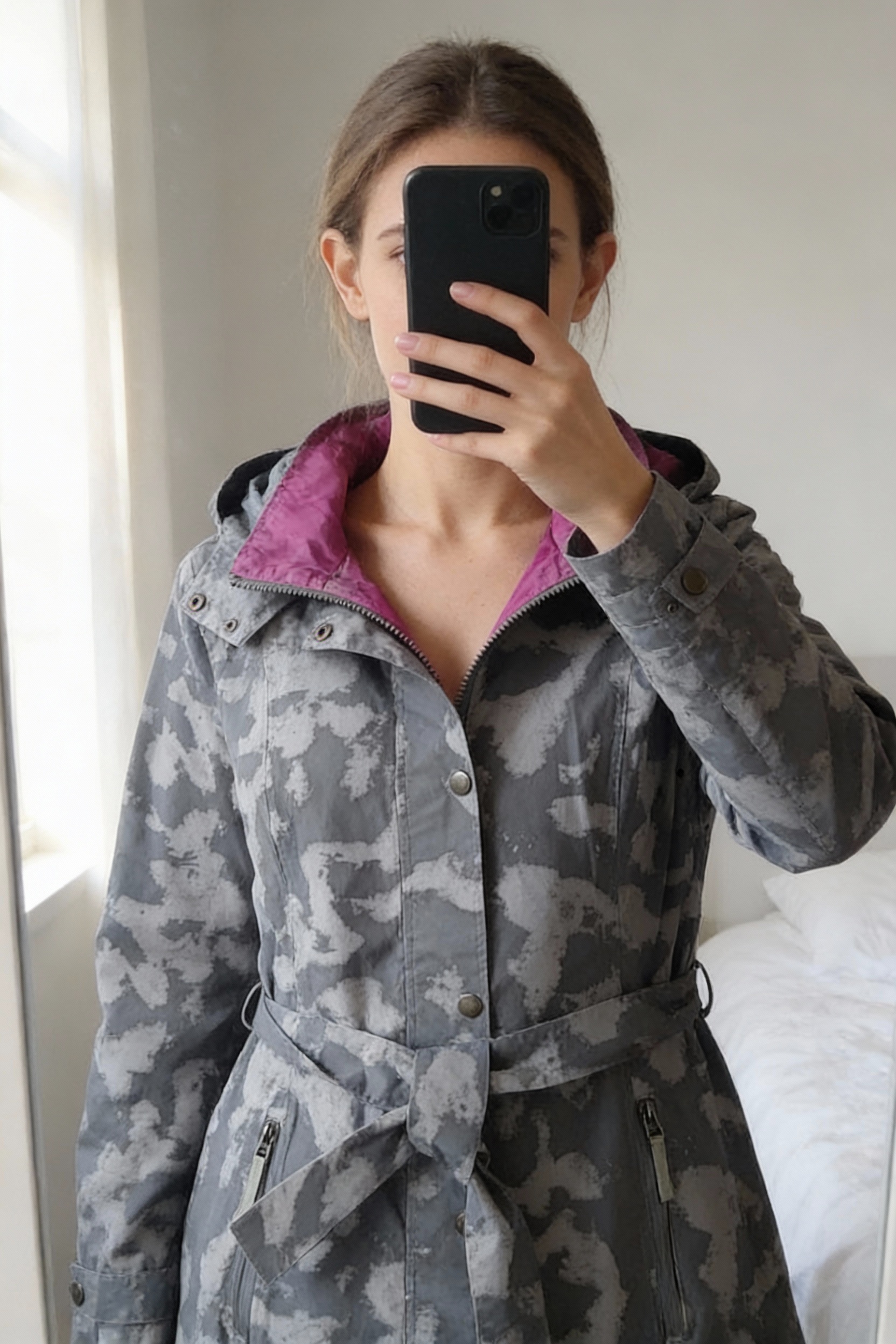 Impermeable trenchcoat size 38EU/ 10UK standing straight facing the camera, in a softly lit bedroom setting, with gentle natural light filtering through a window.