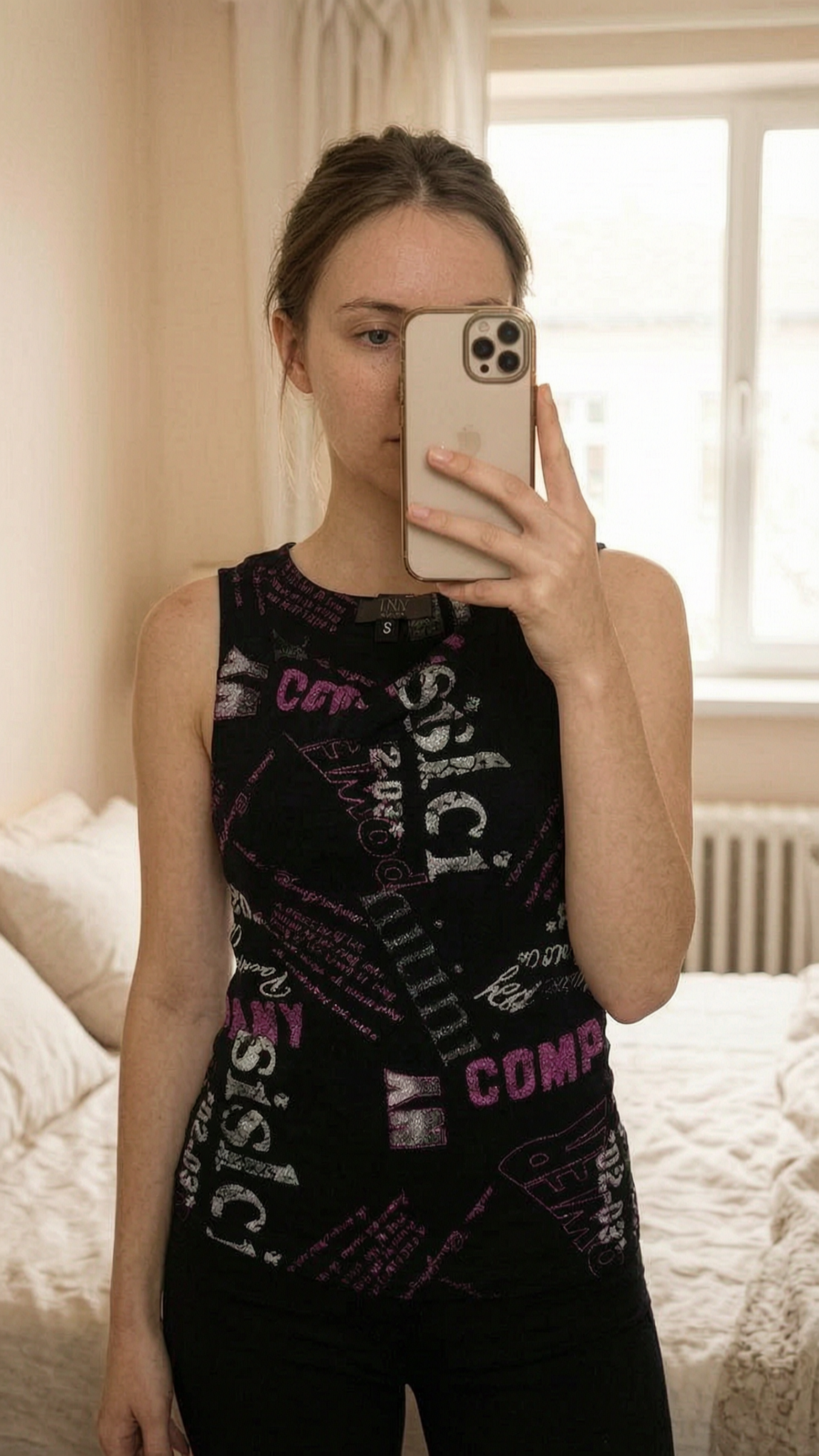 Top Y2K debout, face à la caméra, dans une chambre à la lumière douce, avec une lumière naturelle filtrant par la fenêtre.