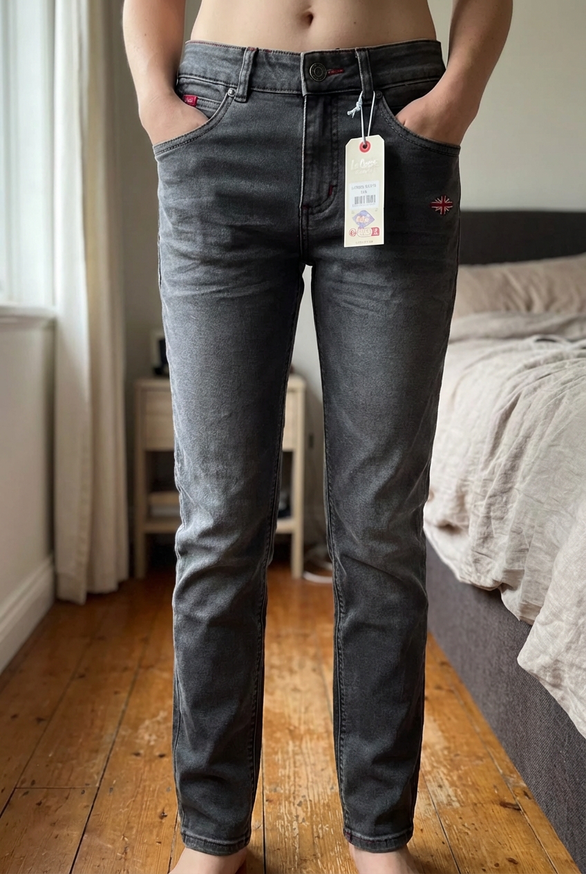 Jeans Lee Cooper neuf 12 ans debout, face à la caméra, dans une chambre à la lumière douce, avec une lumière naturelle filtrant par la fenêtre.