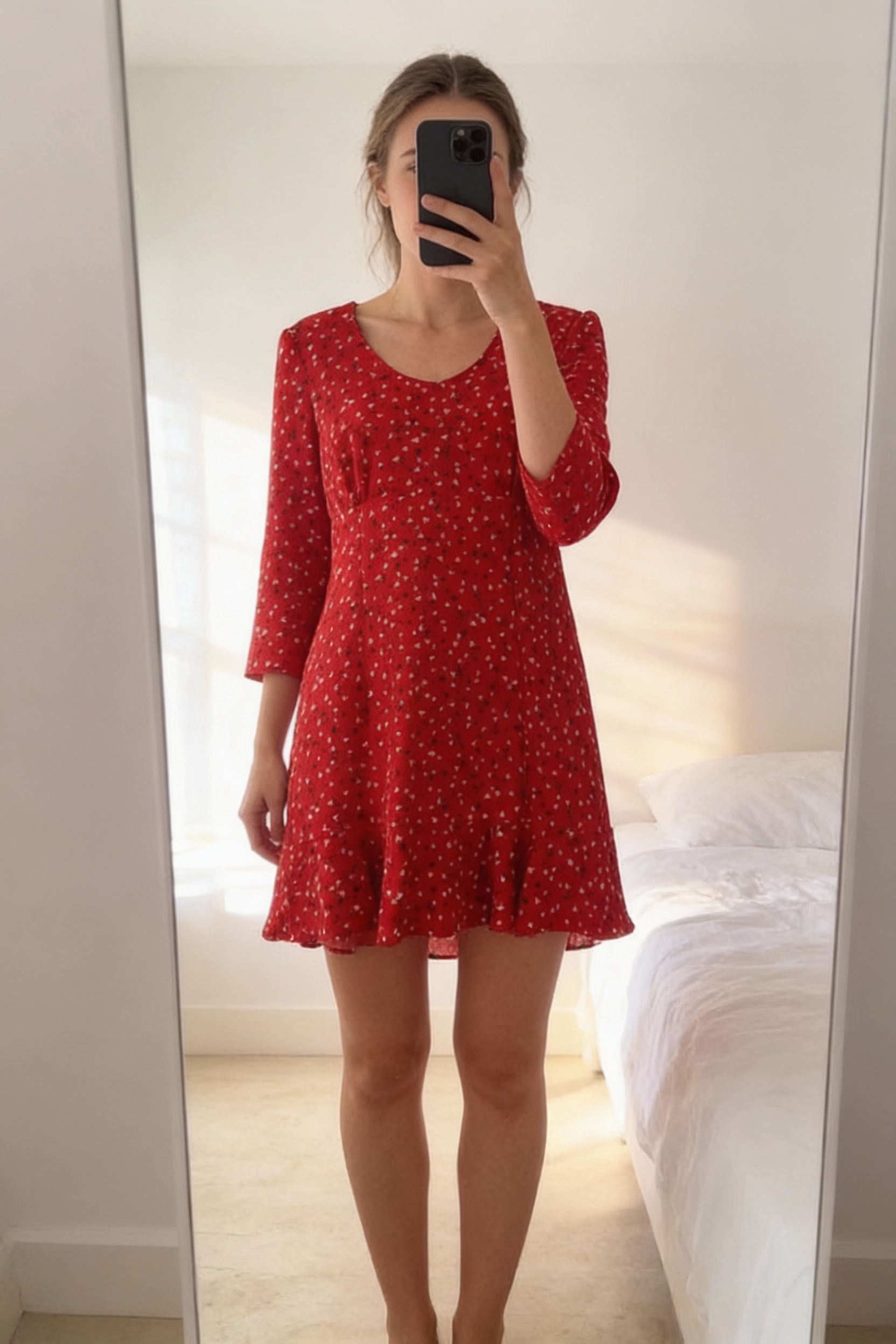 Robe rouge à petits cœurs Naf Naf taille XL vestido rojo corazón debout, face à la caméra, dans une chambre à la lumière douce, avec une lumière naturelle filtrant par la fenêtre.