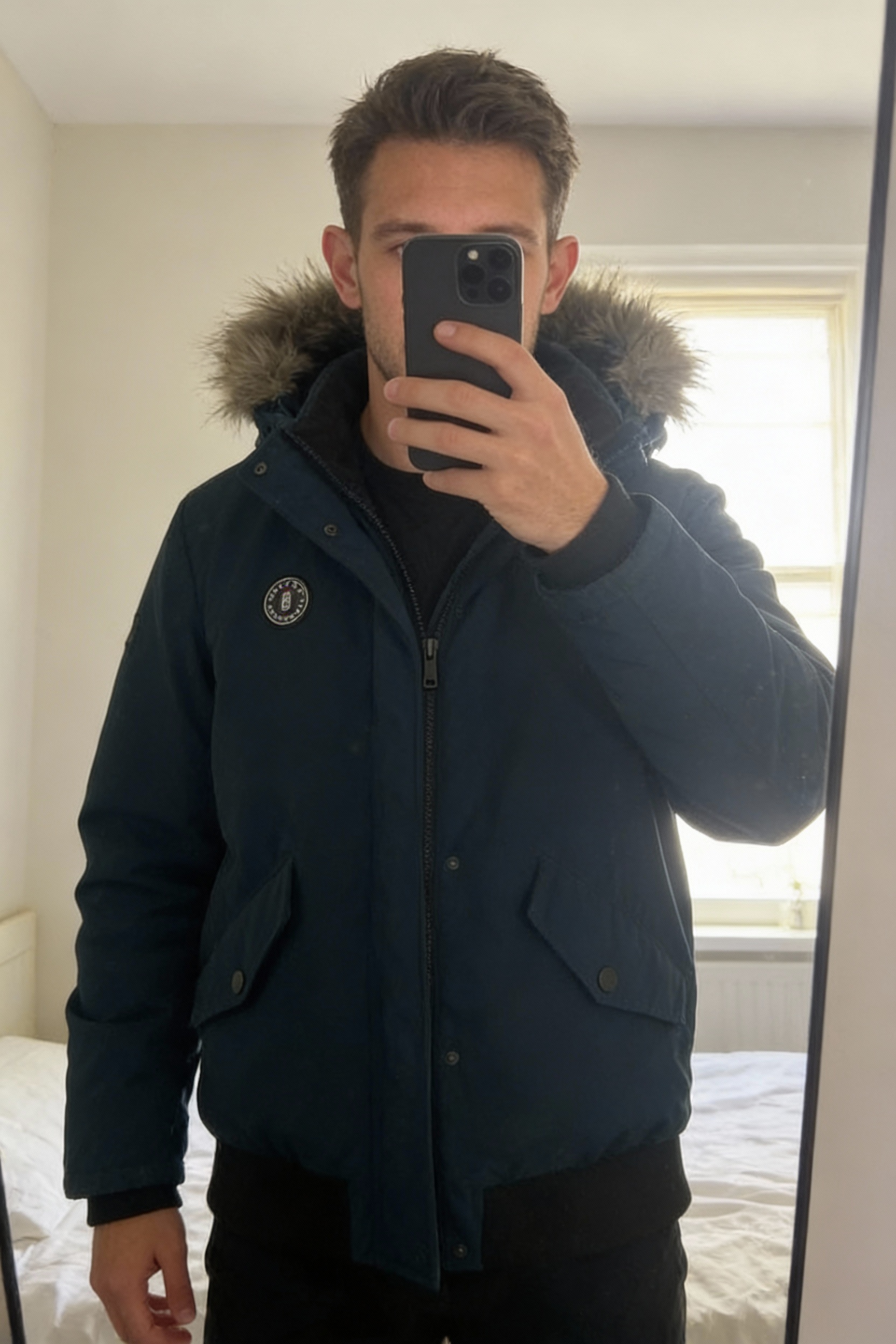 Boys Ted Baker Navy Coat standing straight facing the camera, in a softly lit bedroom setting, with gentle natural light filtering through a window.