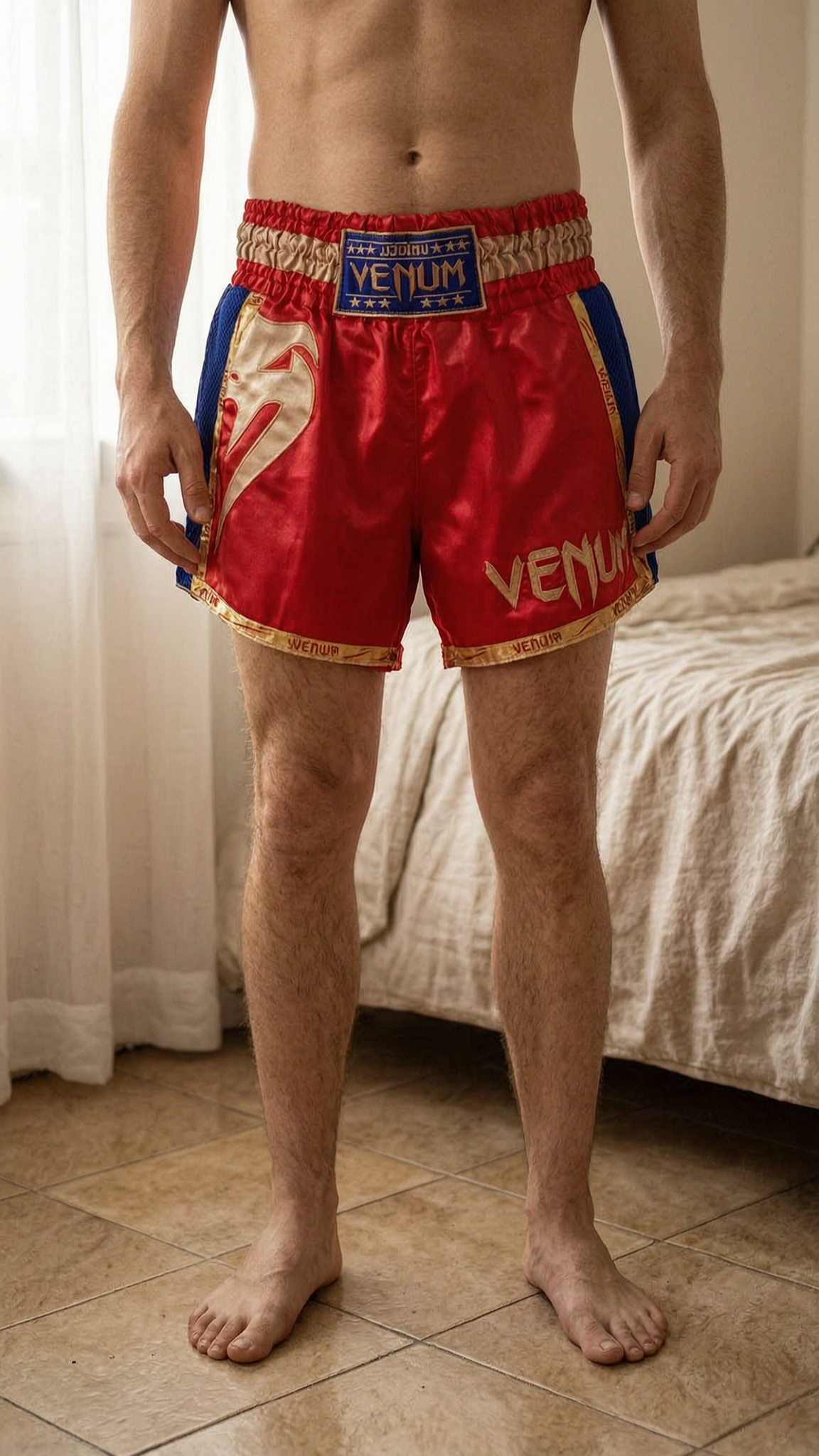 Short de boxe debout, face à la caméra, dans une chambre à la lumière douce, avec une lumière naturelle filtrant par la fenêtre.