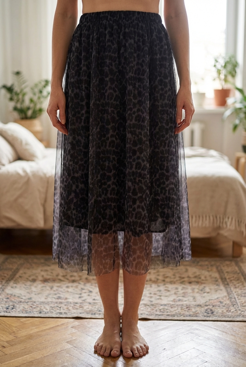 Jupe longue léopard femme TU New Collection debout, face à la caméra, dans une chambre à la lumière douce, avec une lumière naturelle filtrant par la fenêtre.