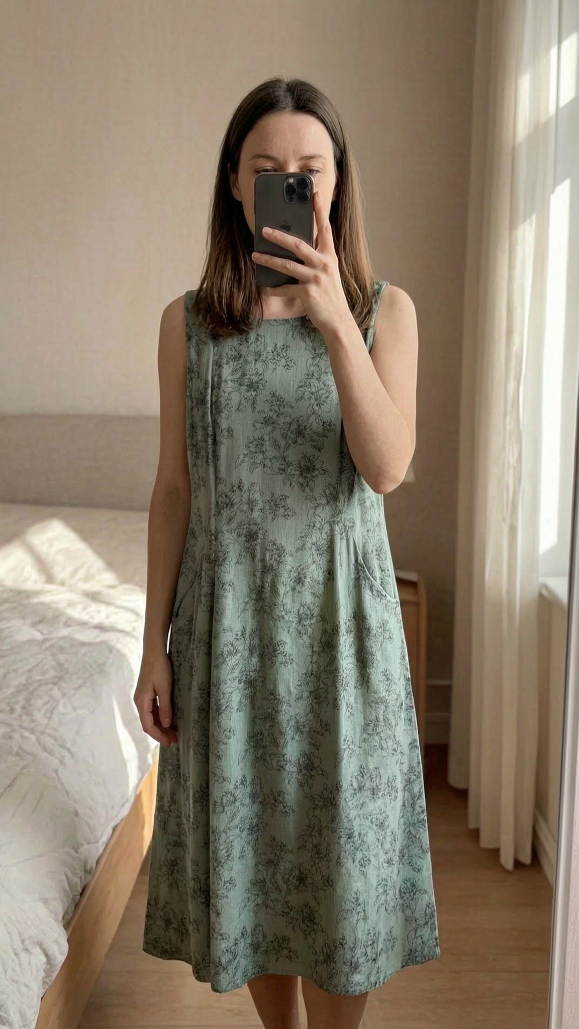 Laura Ashley Midi Dress - Sage Green Floral - UK 10 standing straight facing the camera, in a softly lit bedroom setting, with gentle natural light filtering through a window.