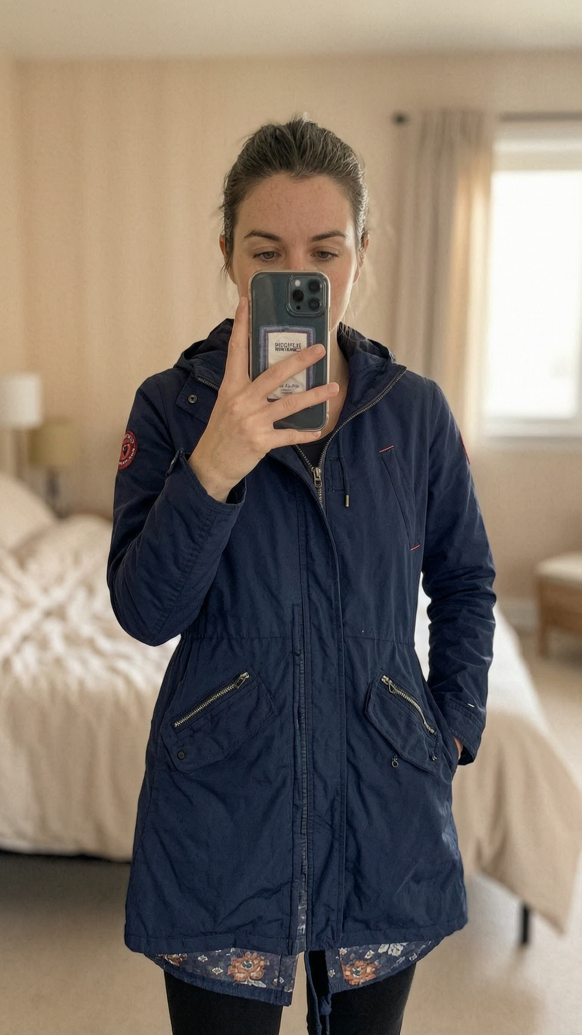 Women’s Tommy Hilfiger Denim Navy Blue Hooded Parka Jacket Size M Floral Lined standing straight facing the camera, in a softly lit bedroom setting, with gentle natural light filtering through a window.