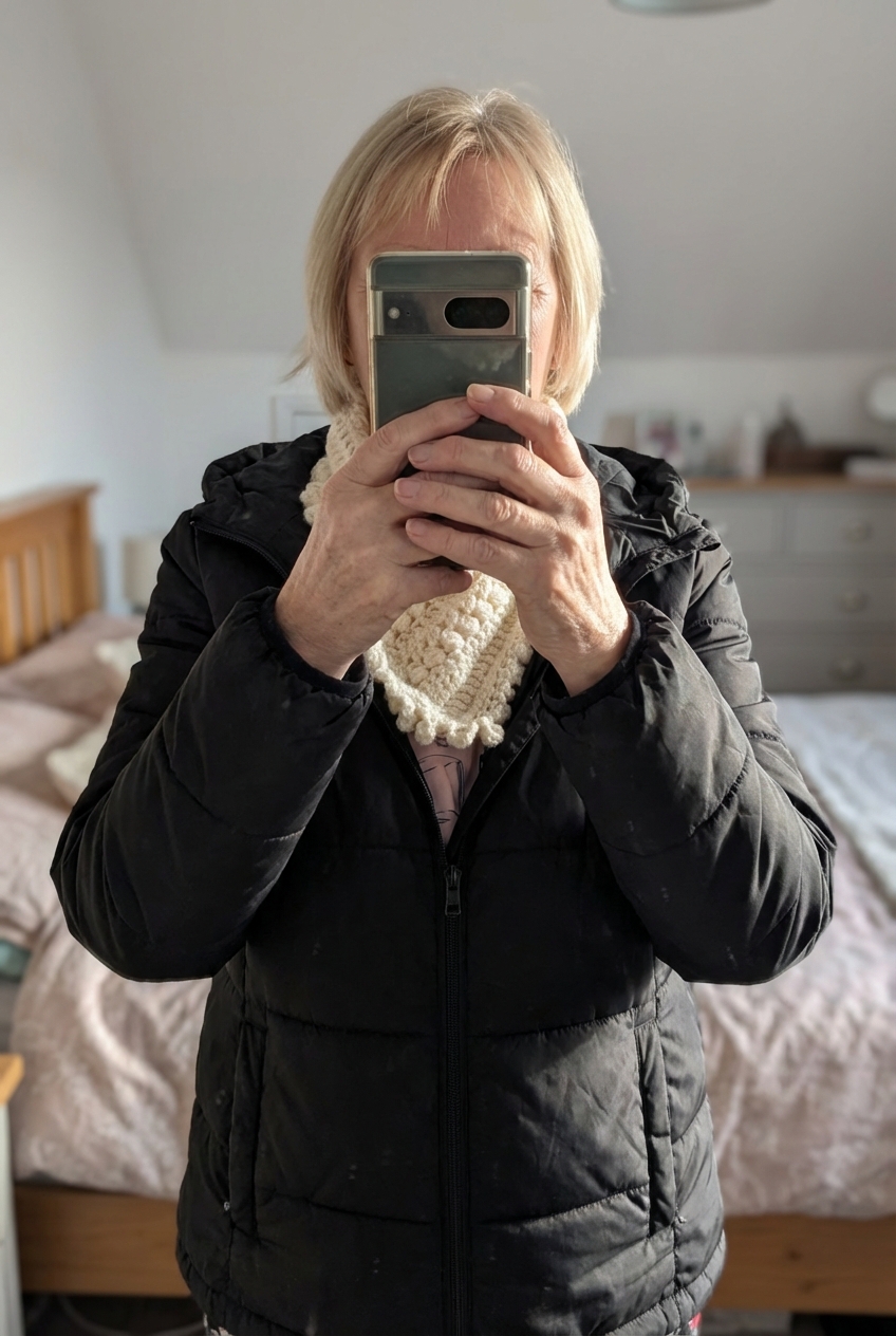 Tour de cou debout, face à la caméra, dans une chambre à la lumière douce, avec une lumière naturelle filtrant par la fenêtre.