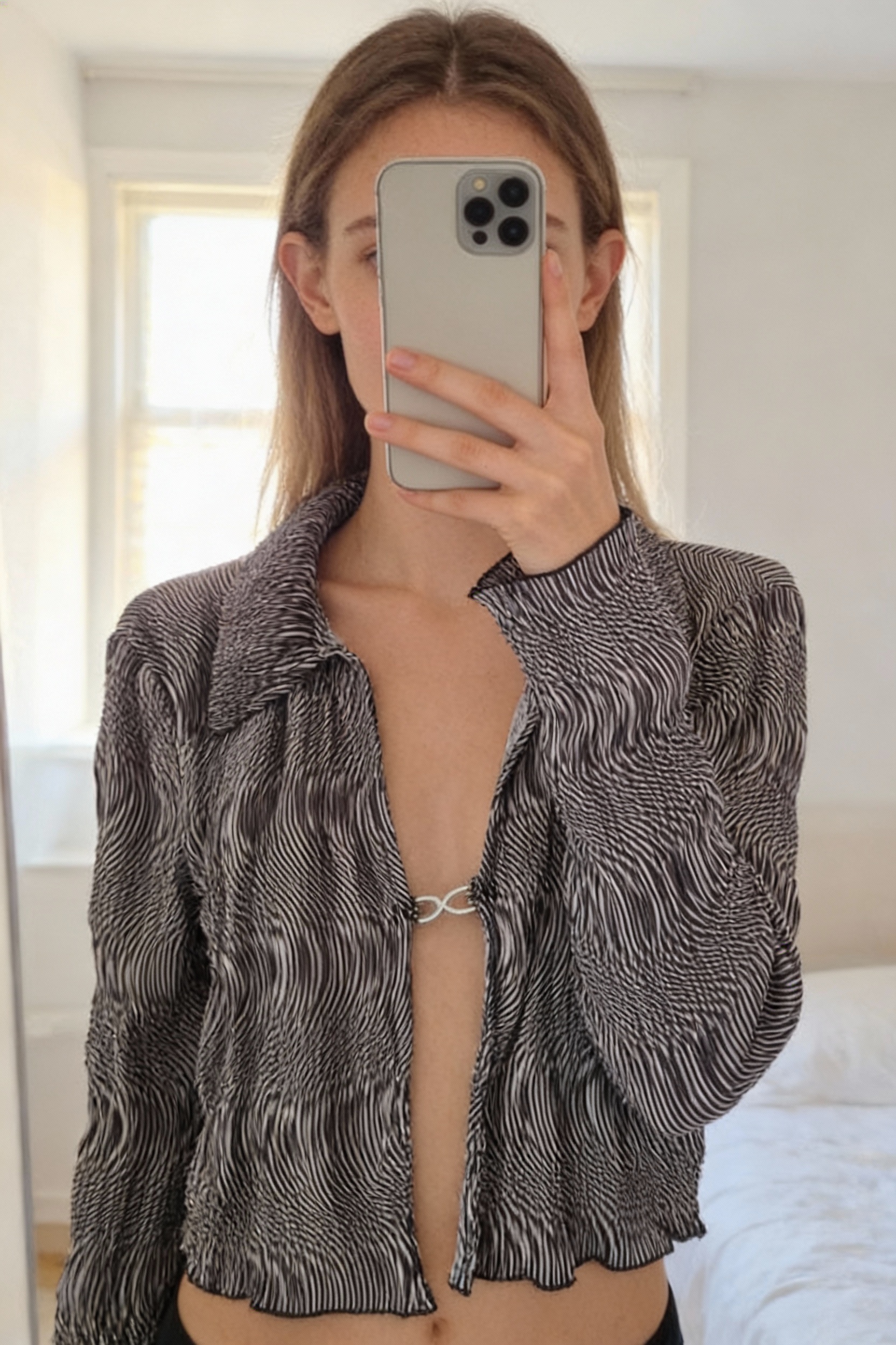 Chemise courte debout, face à la caméra, dans une chambre à la lumière douce, avec une lumière naturelle filtrant par la fenêtre.