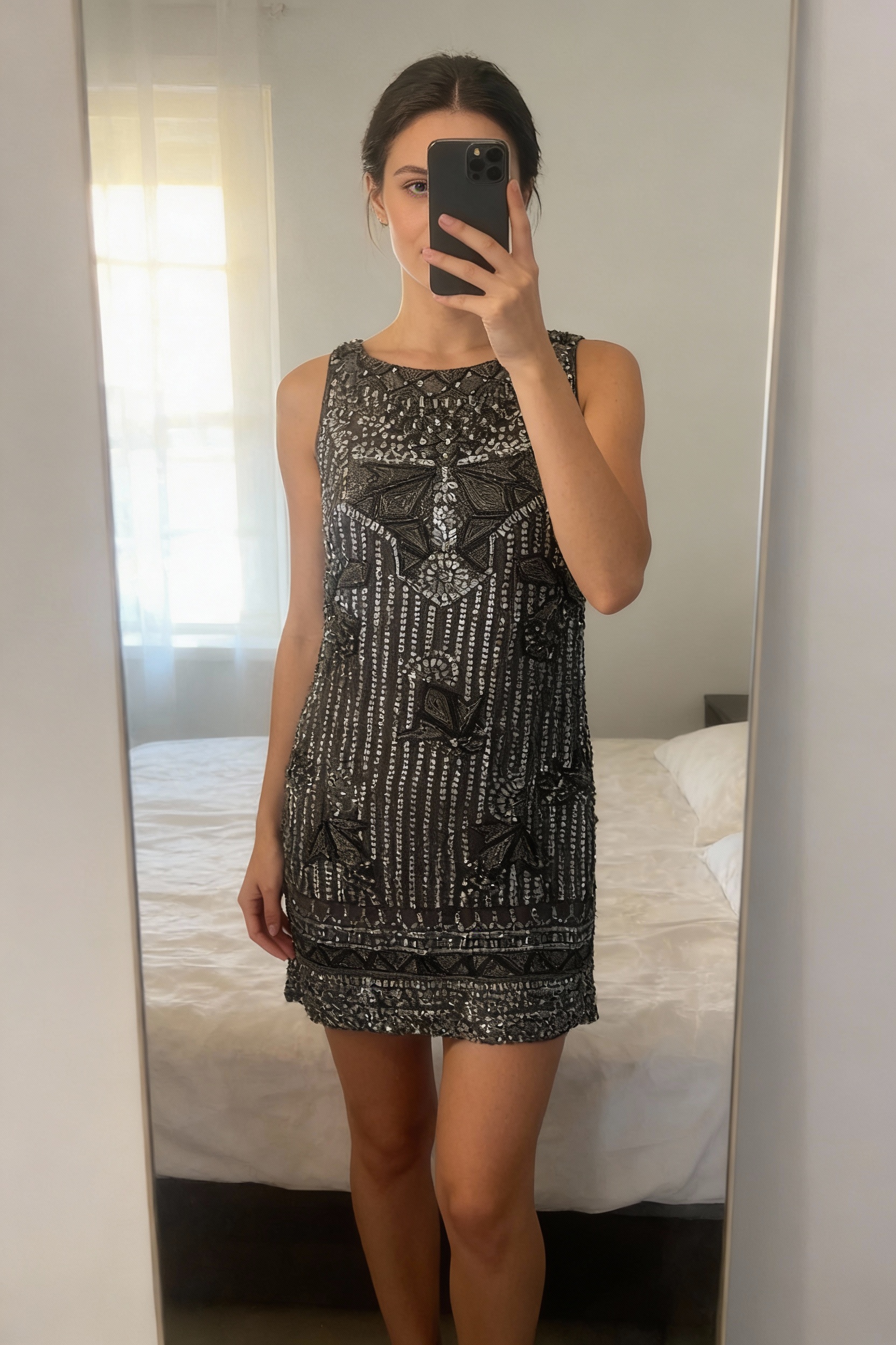 A person in All saints embellished dress size 10 standing straight facing the camera, in a softly lit bedroom setting, with gentle natural light filtering through a window.