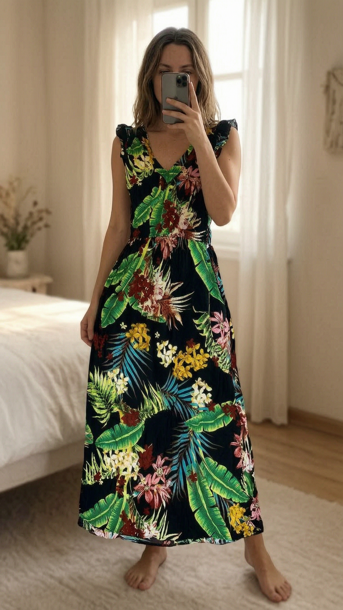 Robe longue fleuri été debout, face à la caméra, dans une chambre à la lumière douce, avec une lumière naturelle filtrant par la fenêtre.