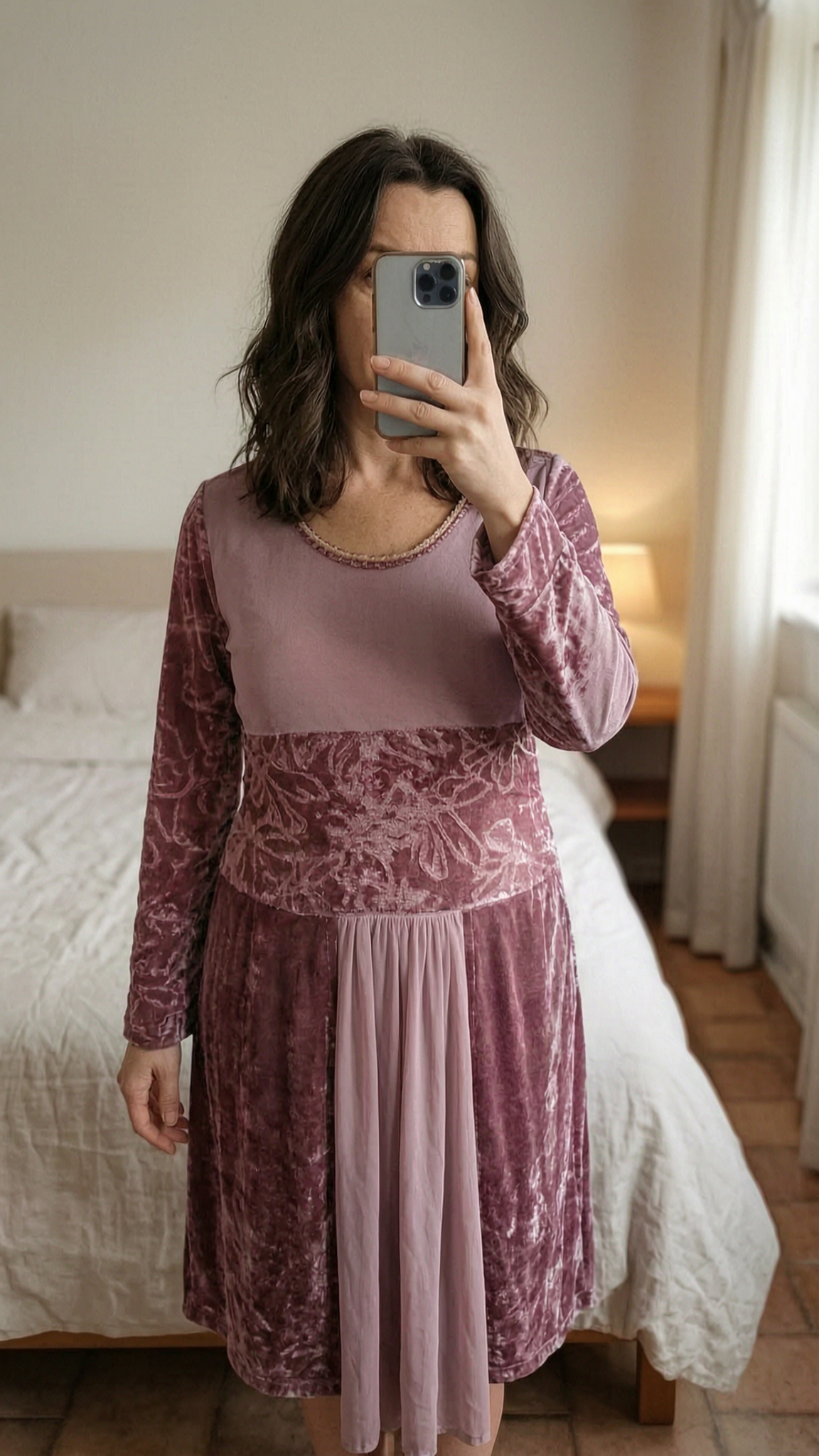 Robe velour fin debout, face à la caméra, dans une chambre à la lumière douce, avec une lumière naturelle filtrant par la fenêtre.