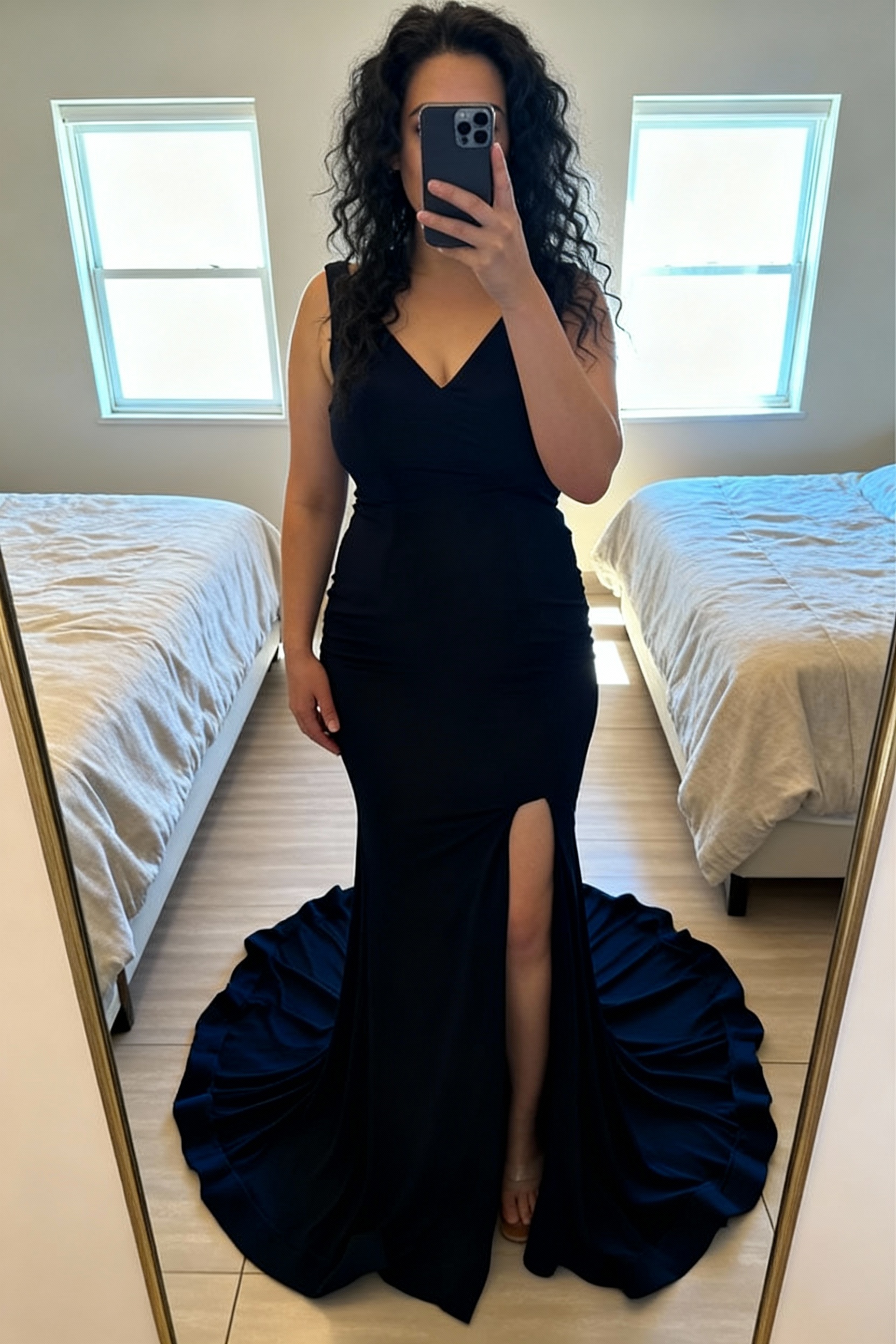 Robe bleu marine debout, face à la caméra, dans une chambre à la lumière douce, avec une lumière naturelle filtrant par la fenêtre.