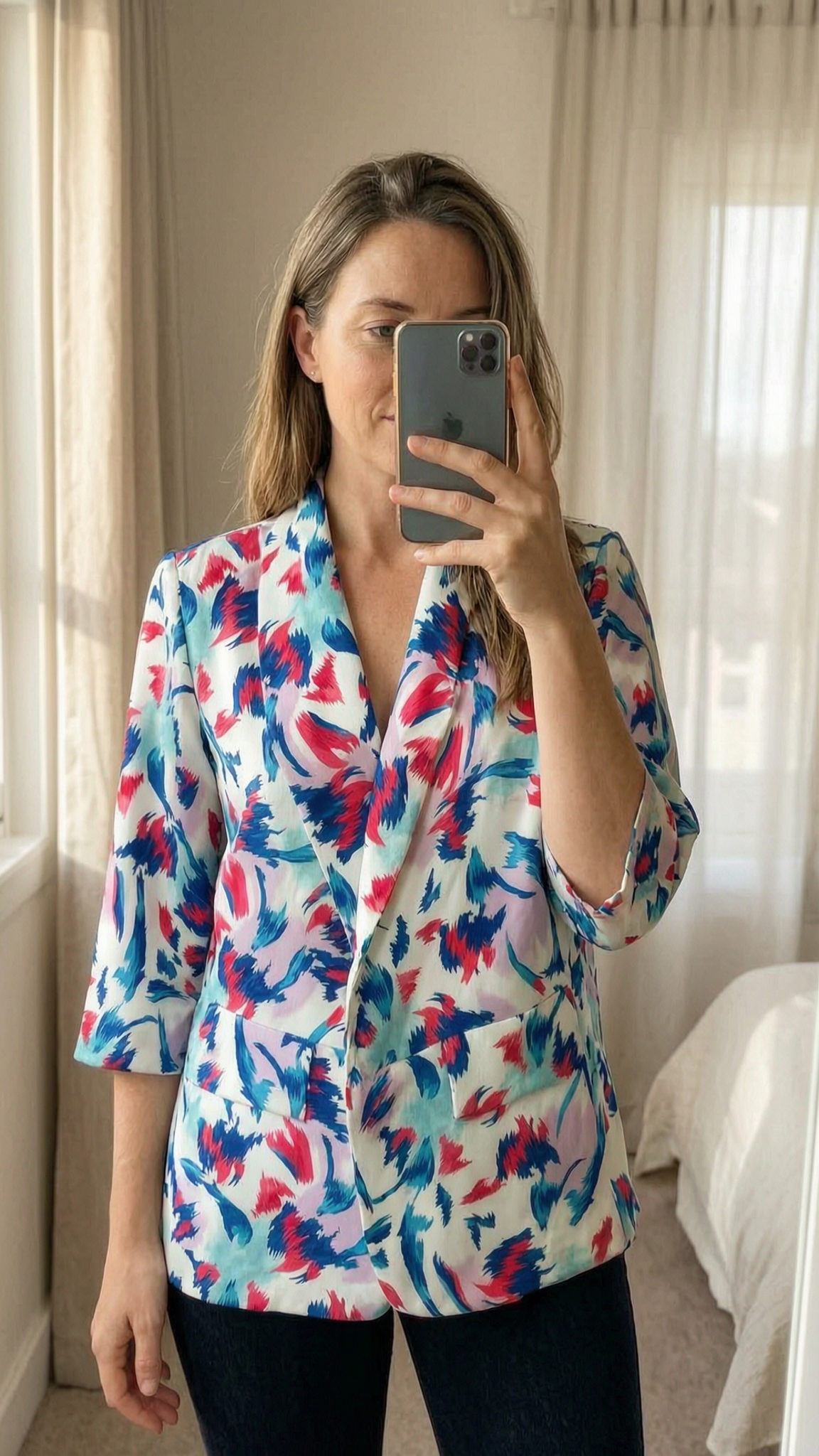 Blazer debout, face à la caméra, dans une chambre à la lumière douce, avec une lumière naturelle filtrant par la fenêtre.