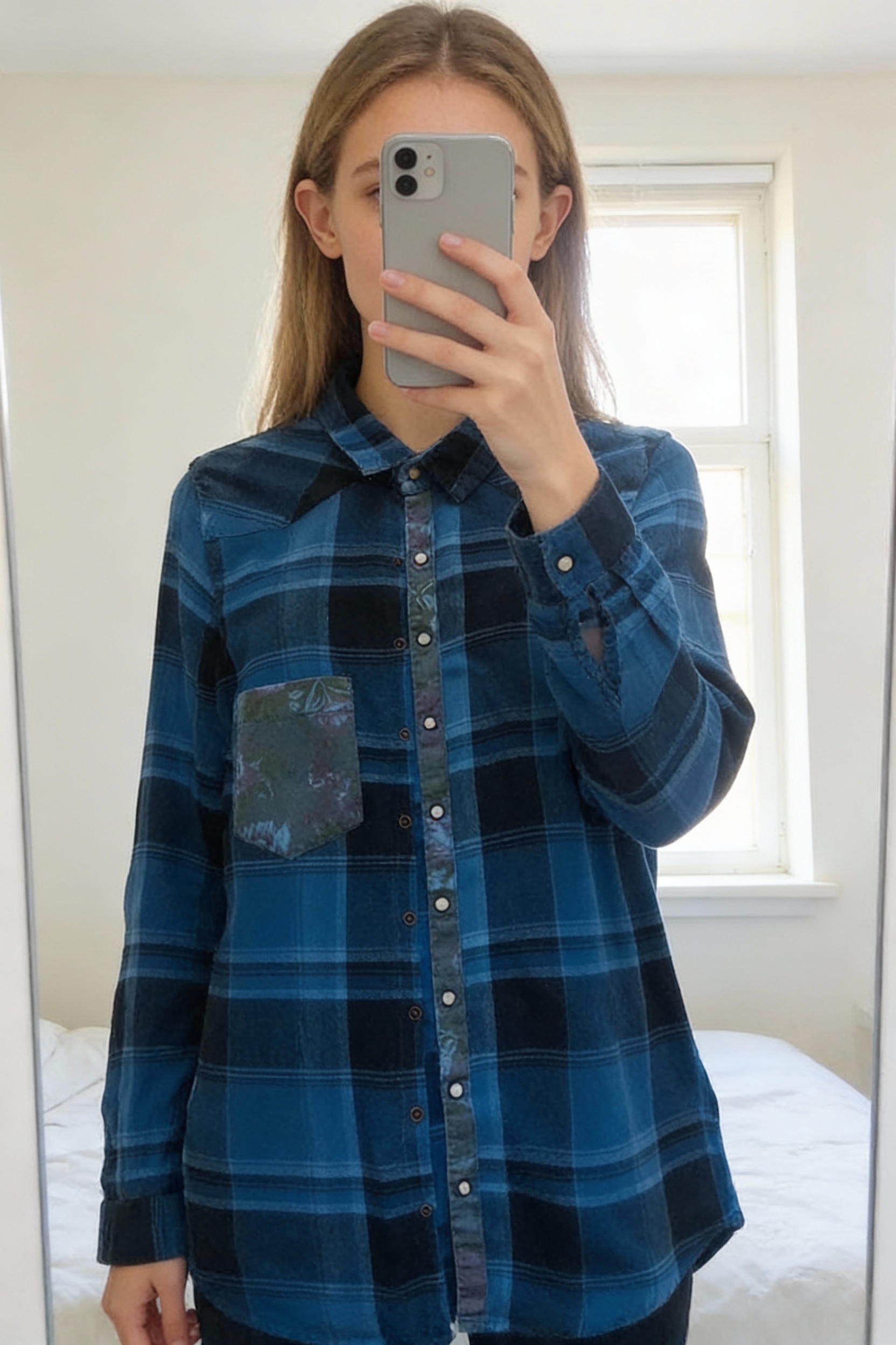 Chemise carreaux debout, face à la caméra, dans une chambre à la lumière douce, avec une lumière naturelle filtrant par la fenêtre.