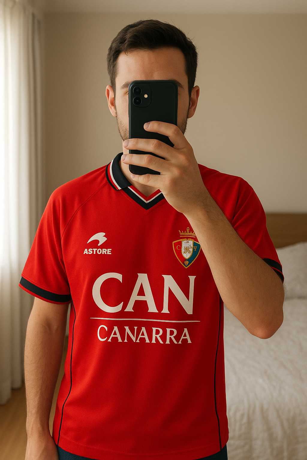 Osasuna vintage collector 2000 officiel debout, face à la caméra, dans une chambre à la lumière douce, avec une lumière naturelle filtrant par la fenêtre.
