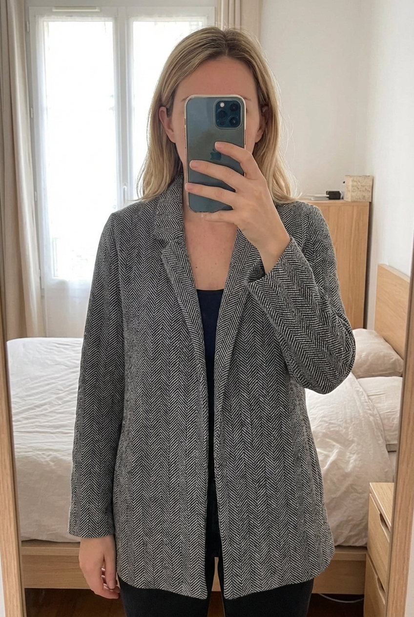 Veste femme grain de malice taille 36 debout, face à la caméra, dans une chambre à la lumière douce, avec une lumière naturelle filtrant par la fenêtre.