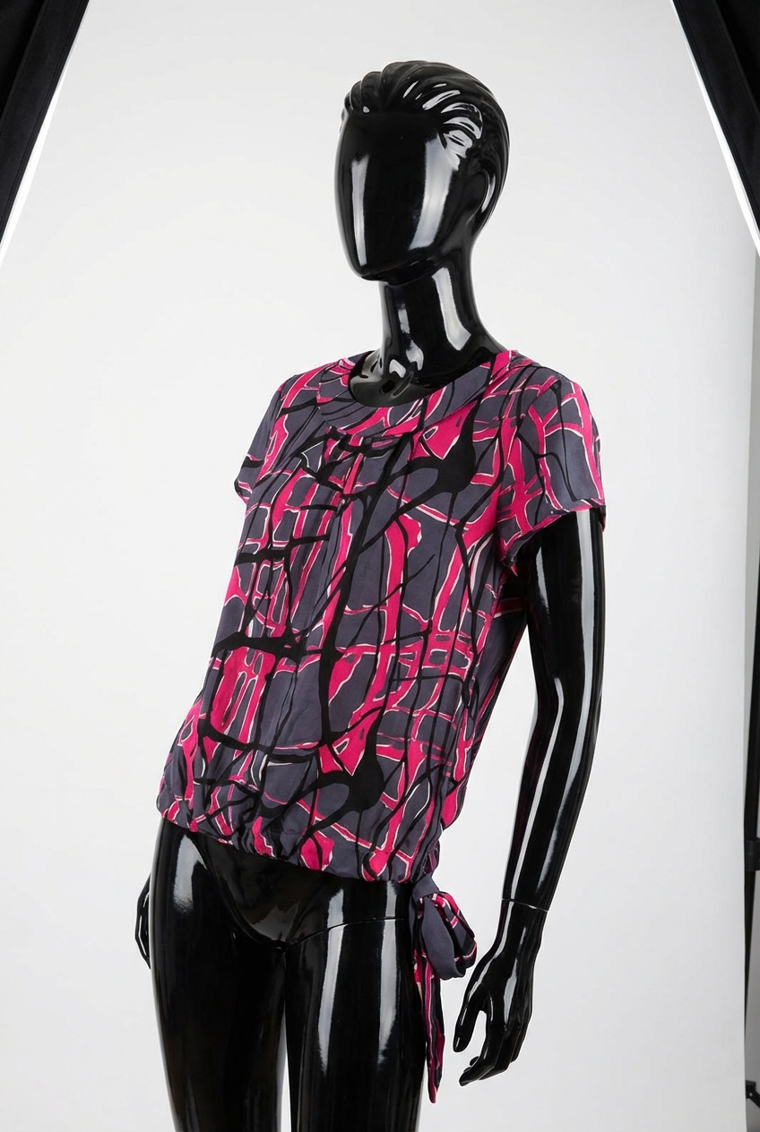 a glossy black plastic mannequin with no facial features in Jaeger Silk Top size 16 Pink, Black & Grey arching their back slightly for a dynamic pose, in a clean photo studio with seamless white backdrop and softbox lighting.