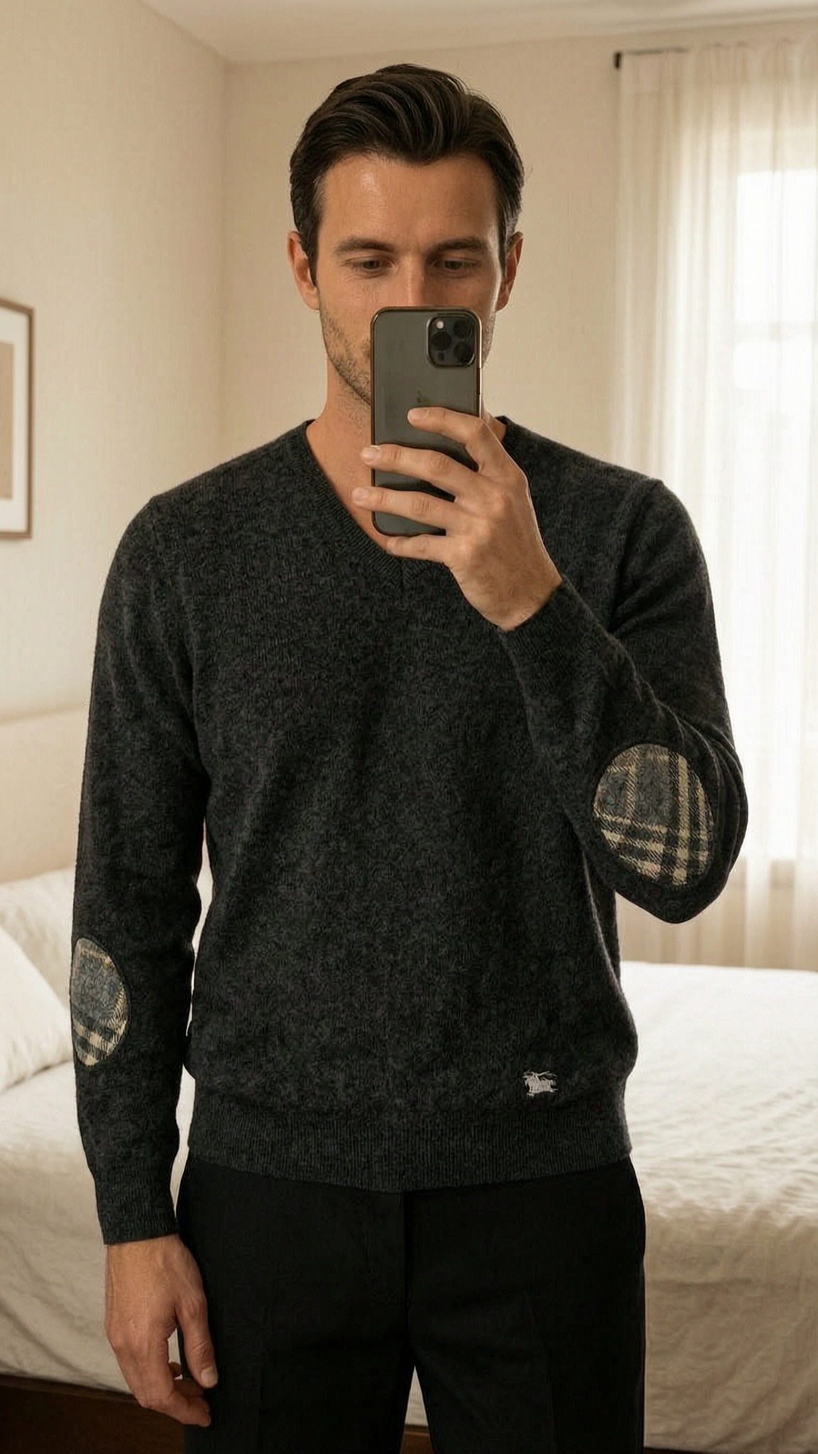 Burberry London jersey gris M lana coderas check vintage Old money premium hombre de pie, mirando a la cámara, en un dormitorio con luz suave y natural filtrándose por la ventana.