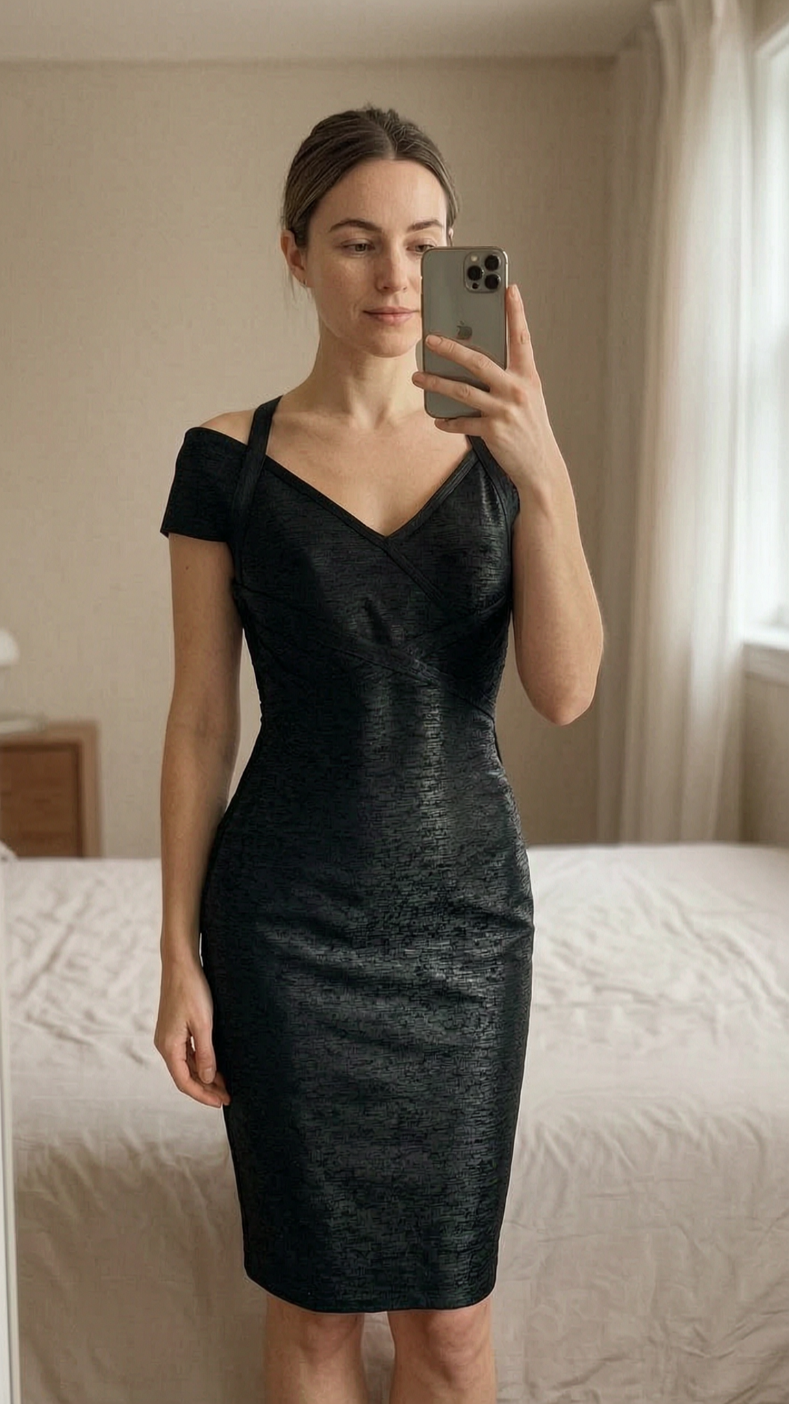 Karen Millen Bodycon Black Dress S standing straight facing the camera, in a softly lit bedroom setting, with gentle natural light filtering through a window.