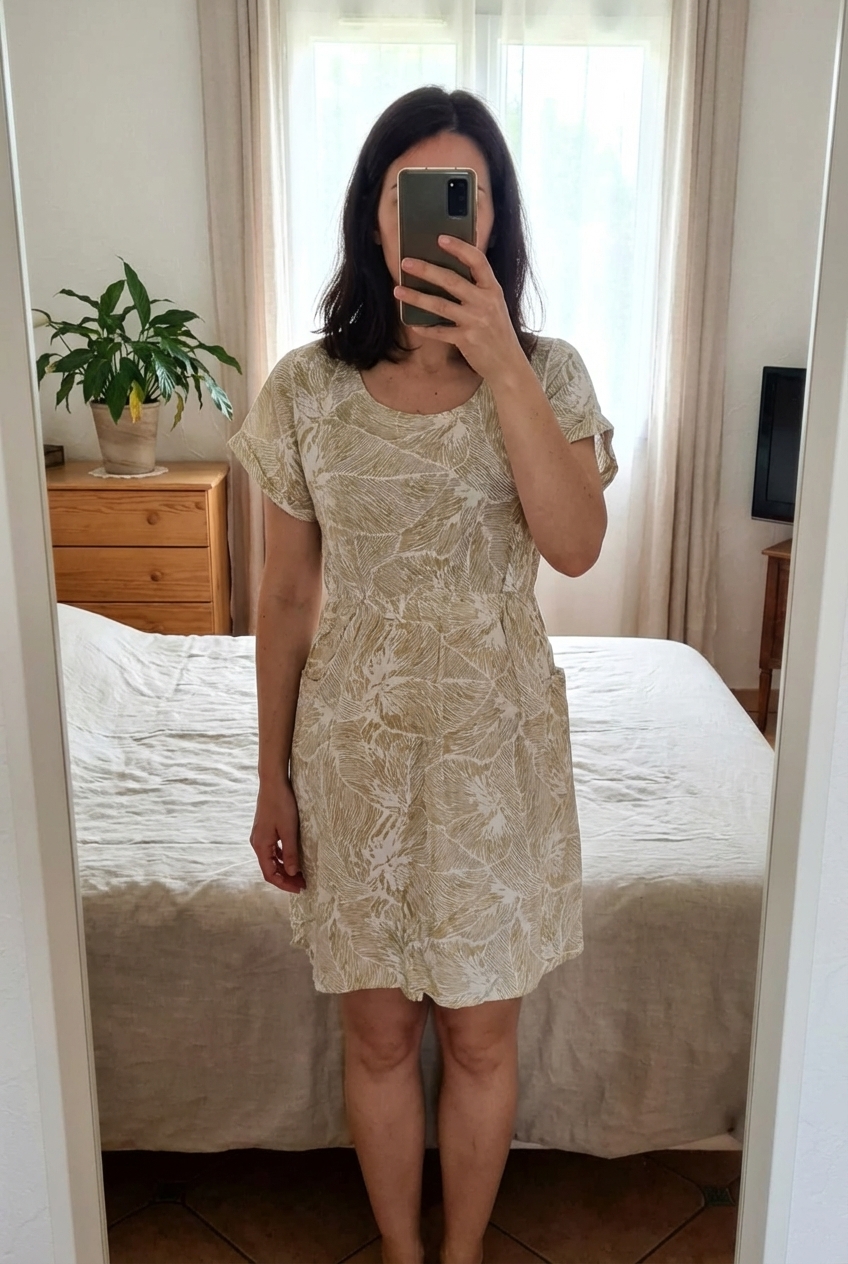 Très jolie robe légère taille 42 debout, face à la caméra, dans une chambre à la lumière douce, avec une lumière naturelle filtrant par la fenêtre.