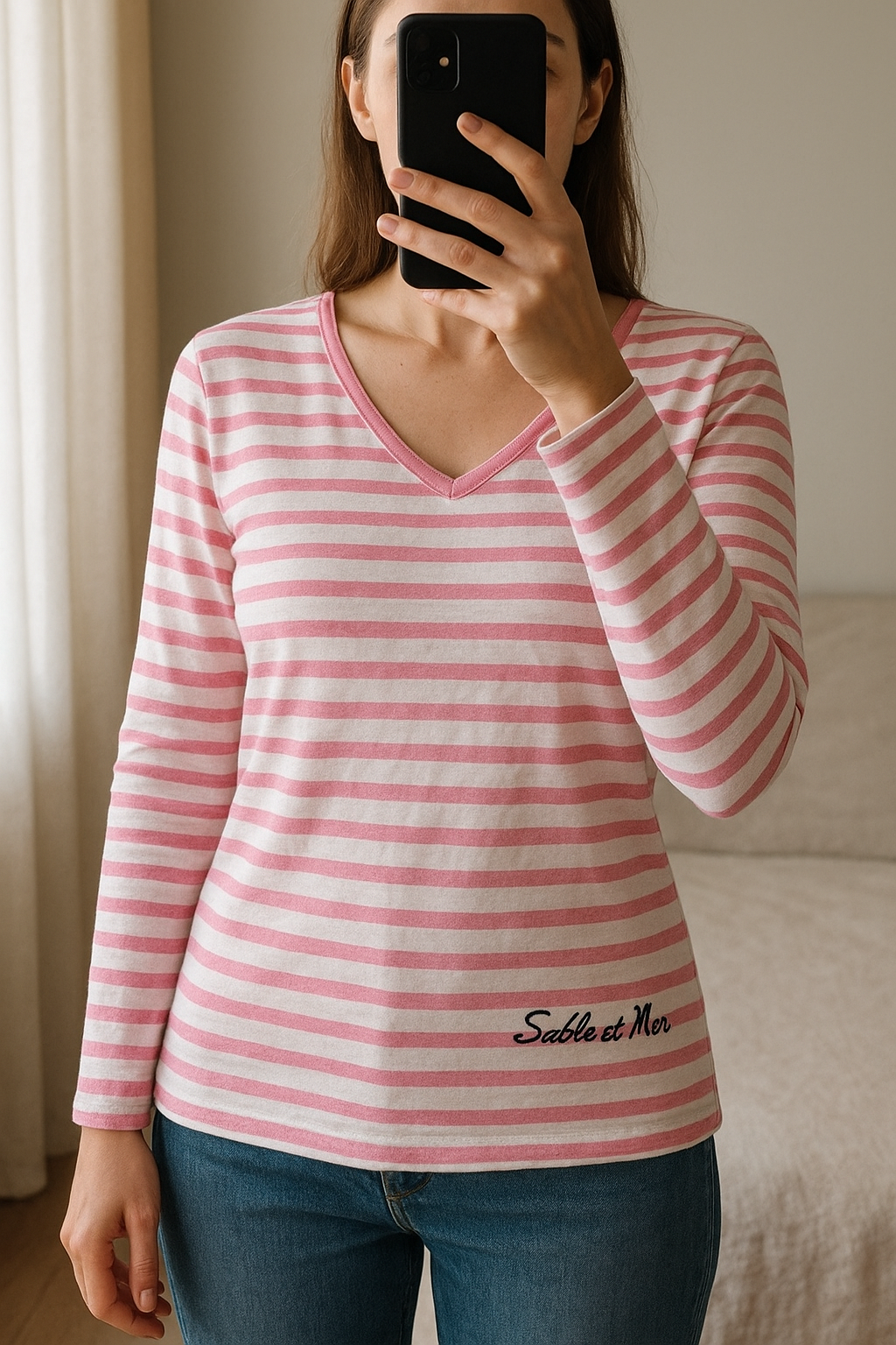 Marinière Rose debout, face à la caméra, dans une chambre à la lumière douce, avec une lumière naturelle filtrant par la fenêtre.