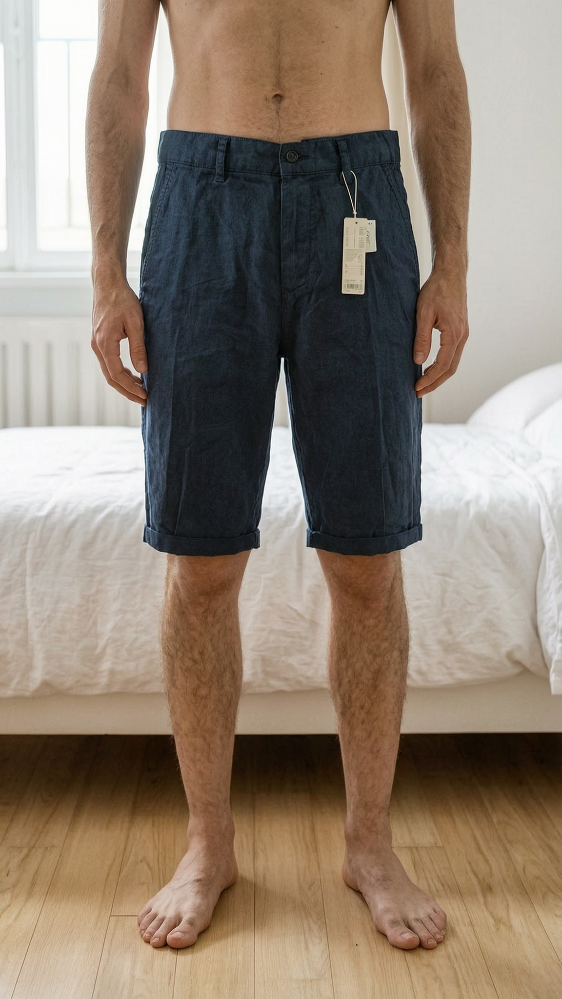 Elegant/versatile linen shorts Esprit size 36 NEW debout, face à la caméra, dans une chambre à la lumière douce, avec une lumière naturelle filtrant par la fenêtre.