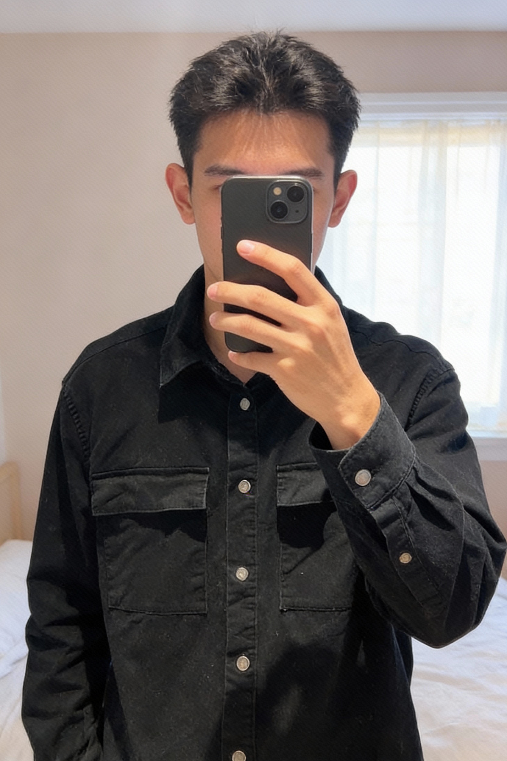 Chemise homme épaisse noir taille M debout, face à la caméra, dans une chambre à la lumière douce, avec une lumière naturelle filtrant par la fenêtre.