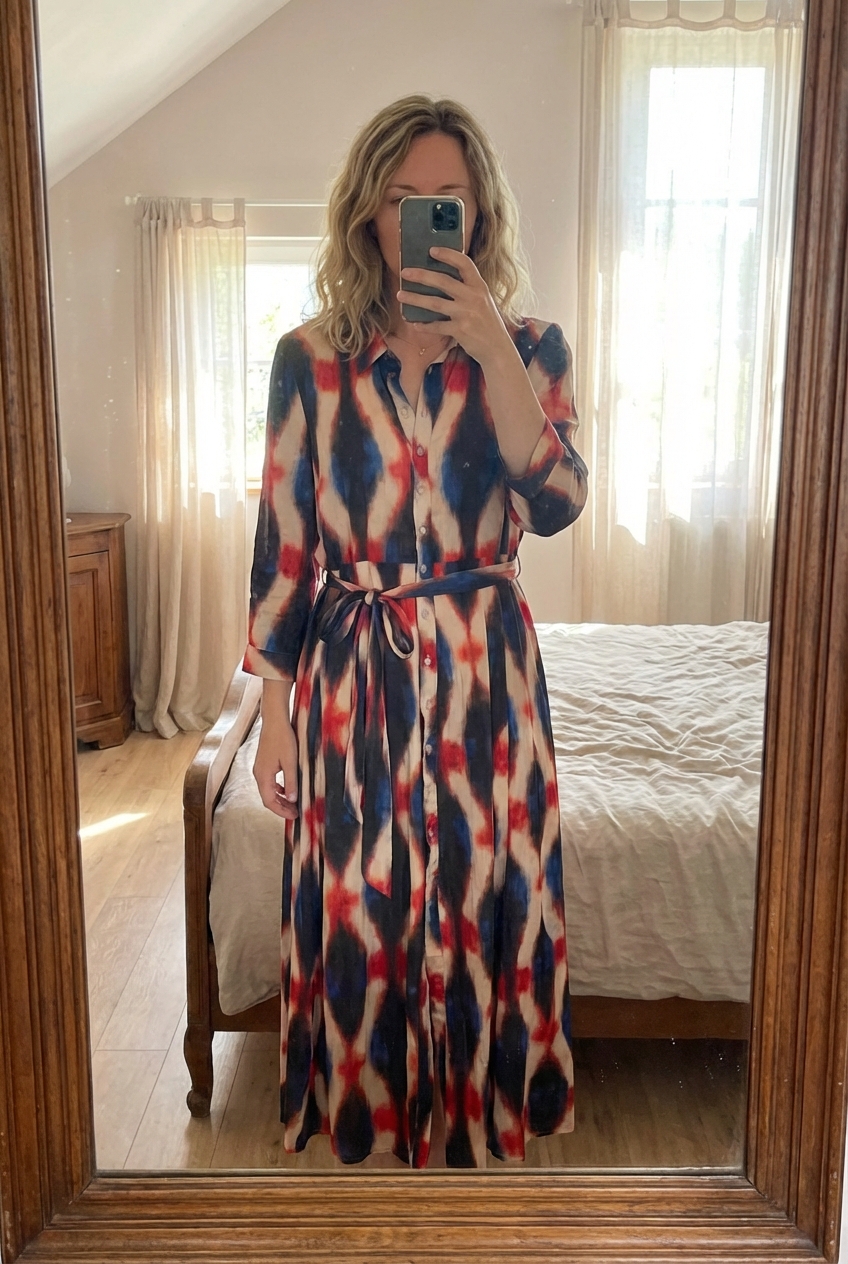 Robe longue GOA debout, face à la caméra, dans une chambre à la lumière douce, avec une lumière naturelle filtrant par la fenêtre.