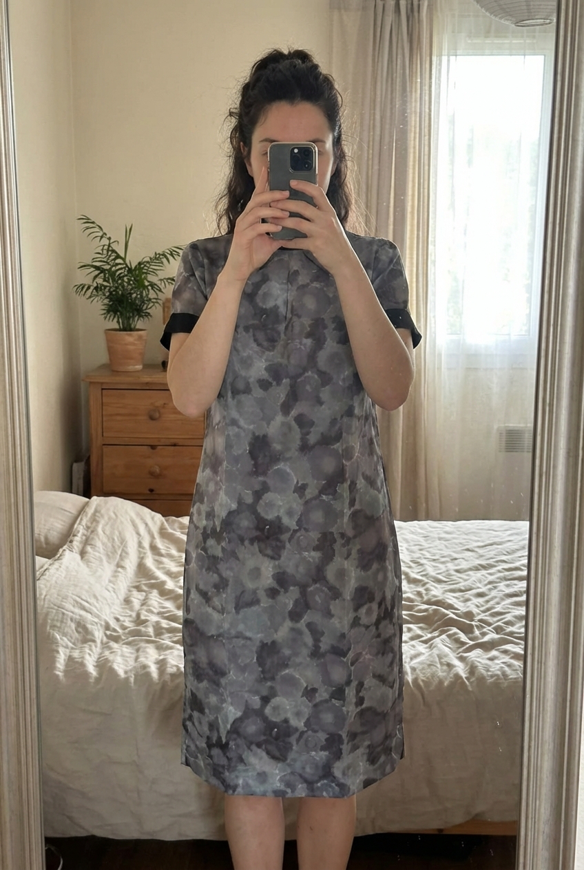 Robe Zara tailles debout, face à la caméra, dans une chambre à la lumière douce, avec une lumière naturelle filtrant par la fenêtre.