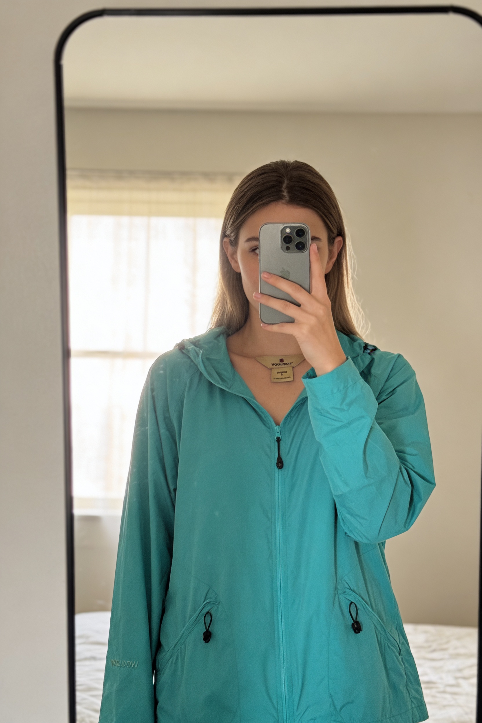 Veste Femme / Woolrich / Bleu turquoise / Taille L debout, face à la caméra, dans une chambre à la lumière douce, avec une lumière naturelle filtrant par la fenêtre.