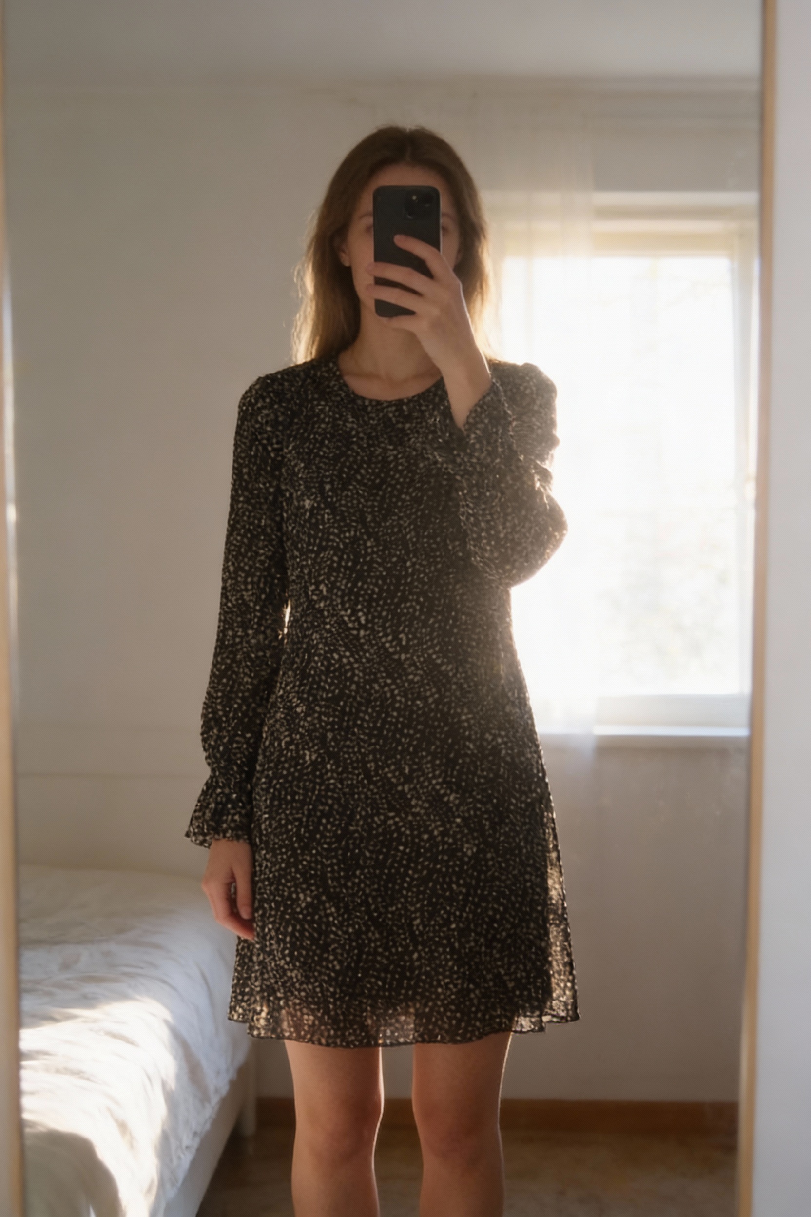 Robe Dona Lisa debout, face à la caméra, dans une chambre à la lumière douce, avec une lumière naturelle filtrant par la fenêtre.