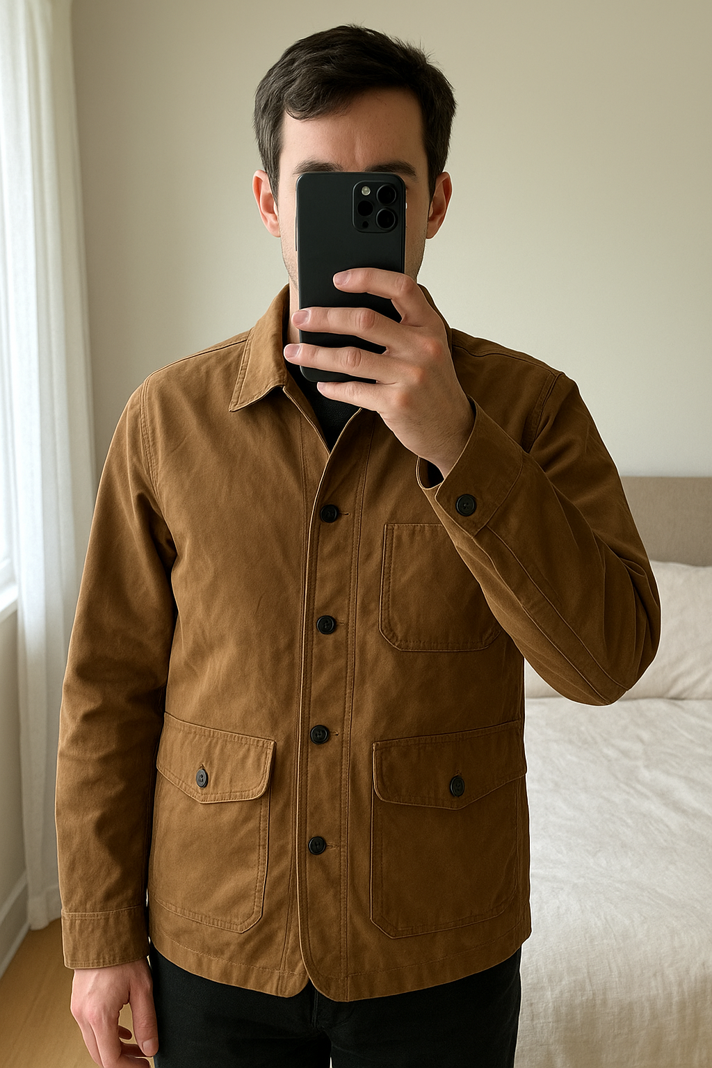 Veste Armani Exchange debout, face à la caméra, dans une chambre à la lumière douce, avec une lumière naturelle filtrant par la fenêtre.