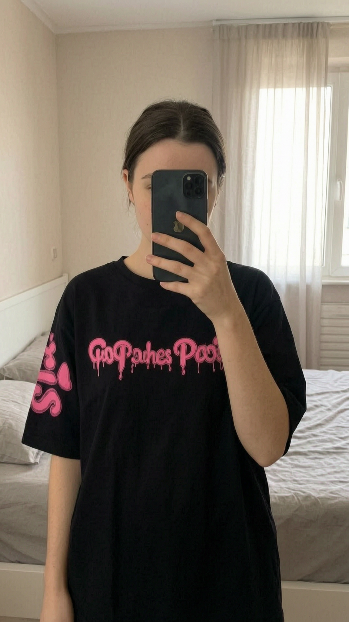 Tee-shirt Riches Paris neuf debout, face à la caméra, dans une chambre à la lumière douce, avec une lumière naturelle filtrant par la fenêtre.