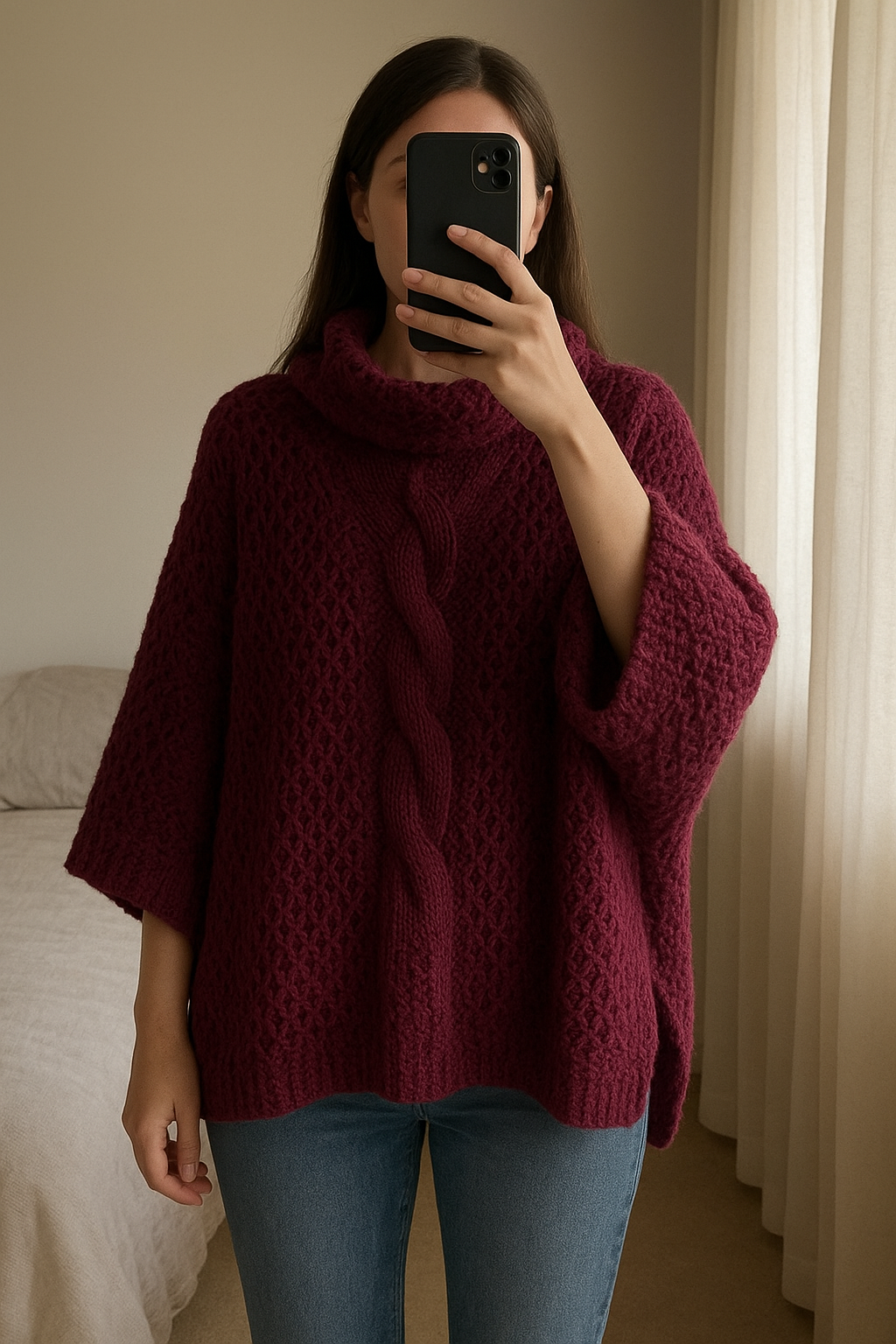 Poncho en laine debout, face à la caméra, dans une chambre à la lumière douce, avec une lumière naturelle filtrant par la fenêtre.