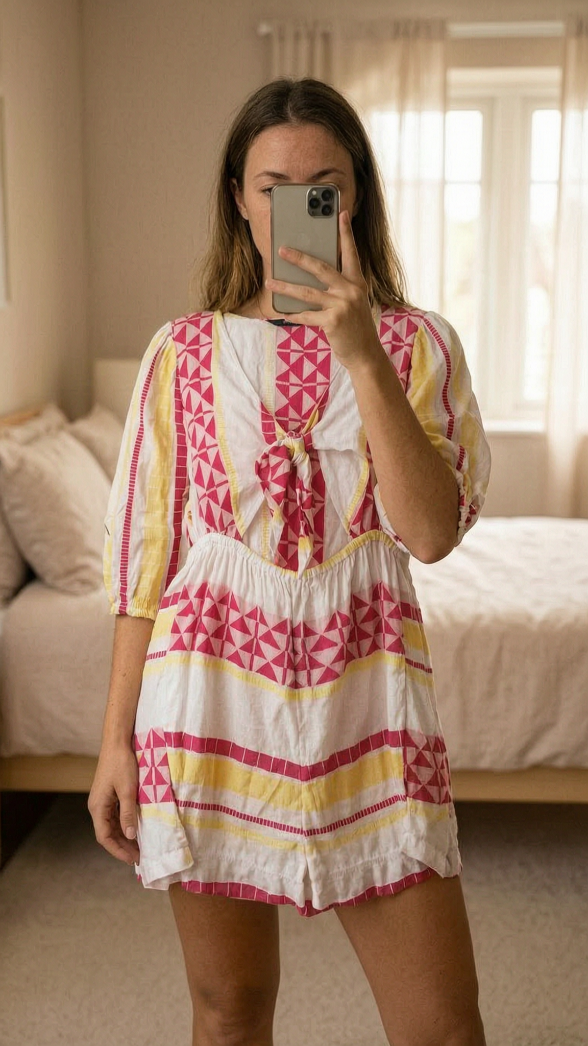 F&F 100% cotton white and pink patterned tie front beack playsuit - size 14 standing straight facing the camera, in a softly lit bedroom setting, with gentle natural light filtering through a window.