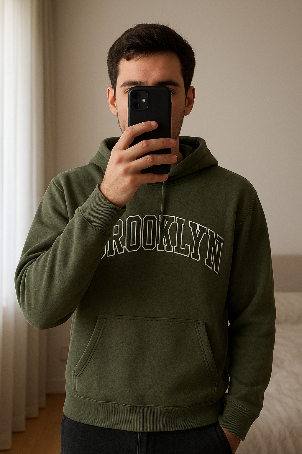 Chlapčenská zelená mikina standing straight facing the camera, in a softly lit bedroom setting, with gentle natural light filtering through a window.