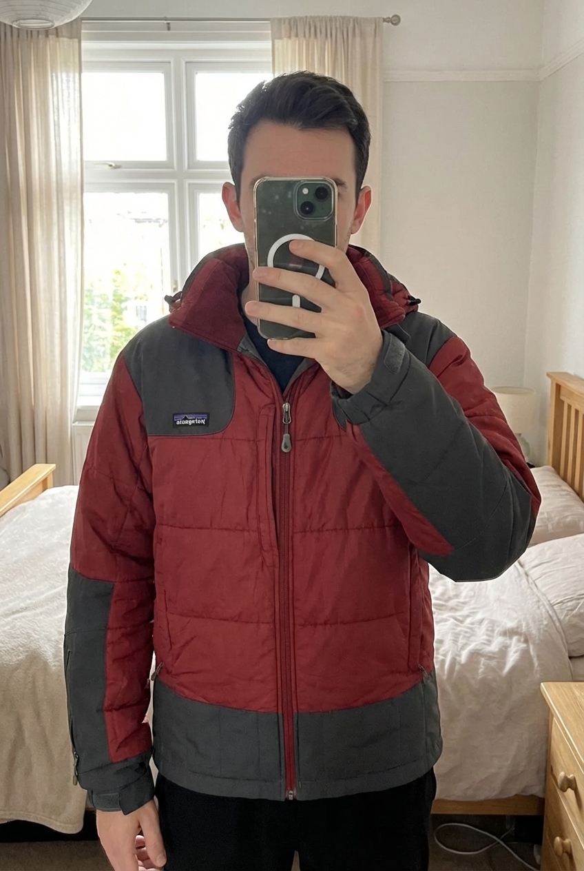 Parka Patagonia Homme! de pie, mirando a la cámara, en un dormitorio con luz suave y natural filtrándose por la ventana.