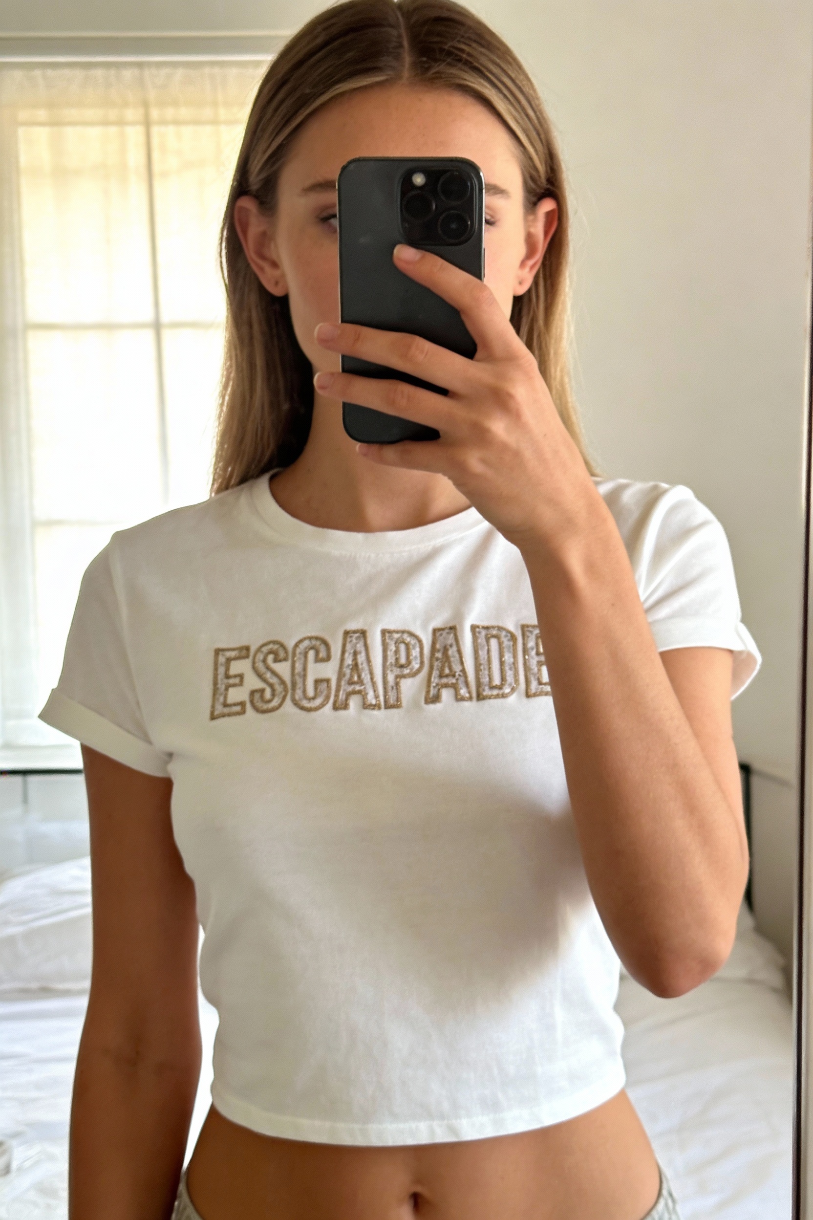 Tee shirt Maison 123 taille S debout, face à la caméra, dans une chambre à la lumière douce, avec une lumière naturelle filtrant par la fenêtre.