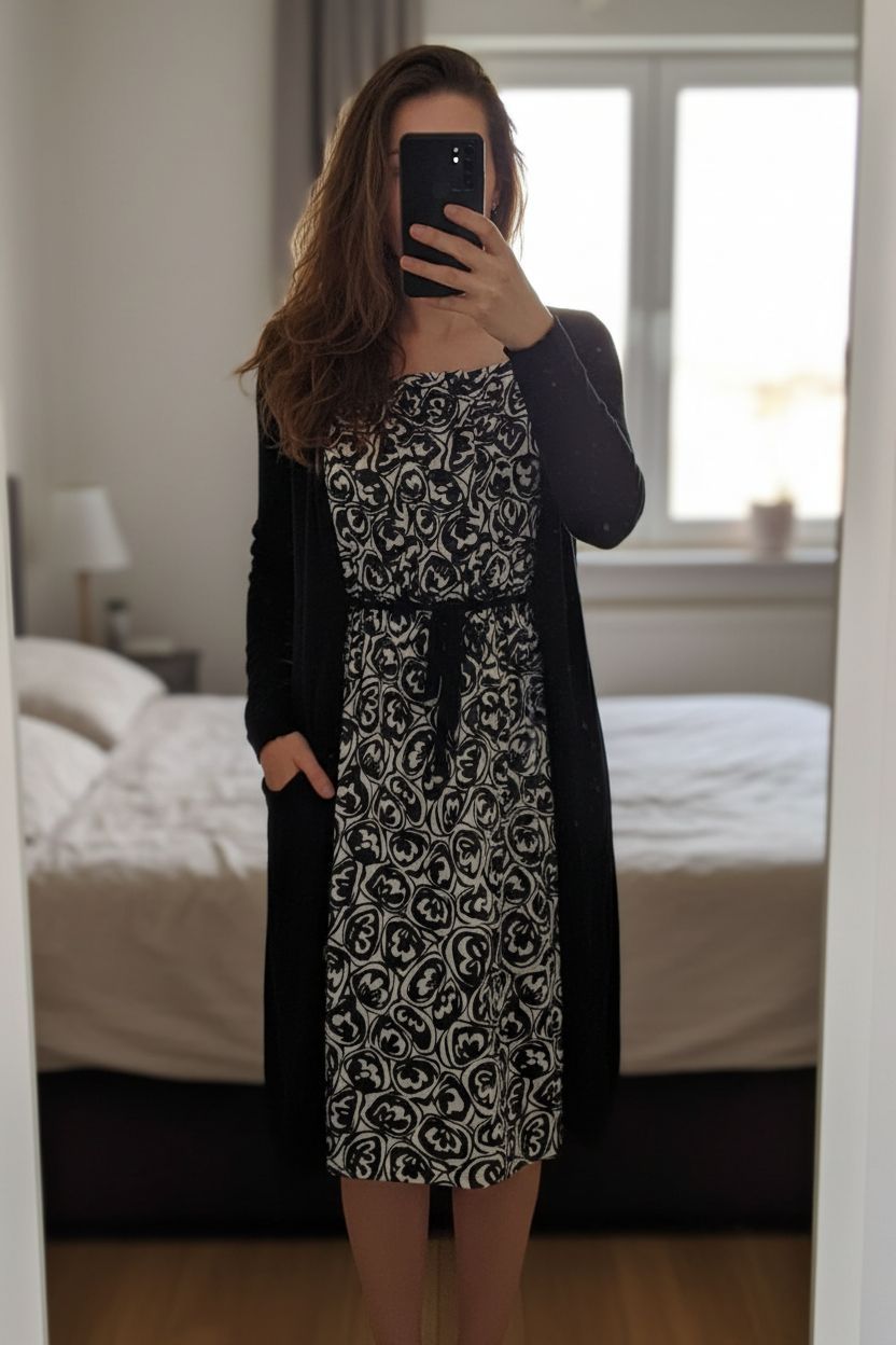 Original vestido negro y blanco / Robe midi noire de pie, mirando a la cámara, en un dormitorio con luz suave y natural filtrándose por la ventana.