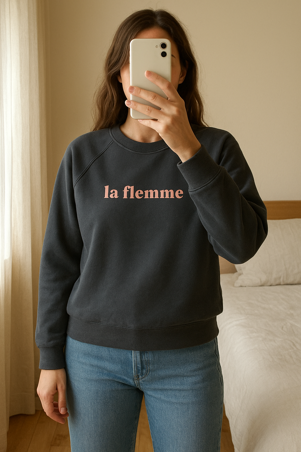 Sweat de sport, "la flemme" Kiabi, gris foncé et rose debout, face à la caméra, dans une chambre à la lumière douce, avec une lumière naturelle filtrant par la fenêtre.
