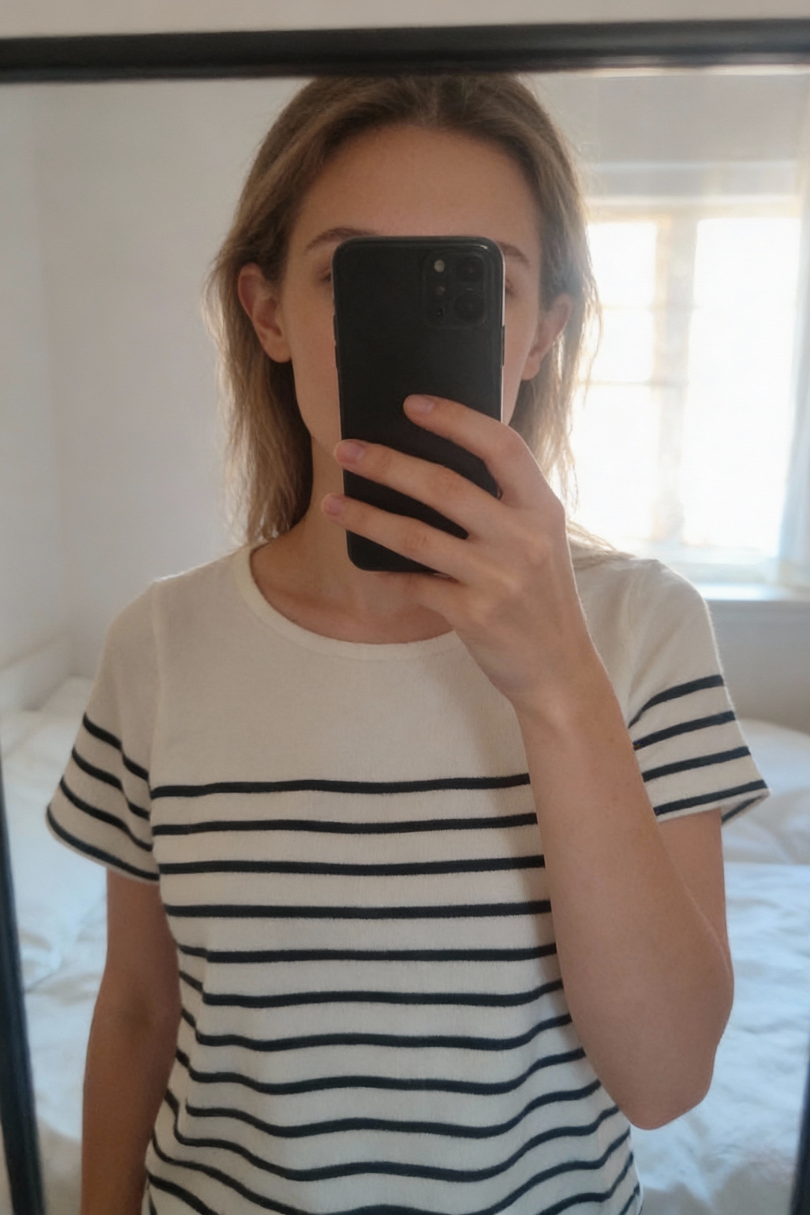 Marinière marque japonaise Taille L debout, face à la caméra, dans une chambre à la lumière douce, avec une lumière naturelle filtrant par la fenêtre.